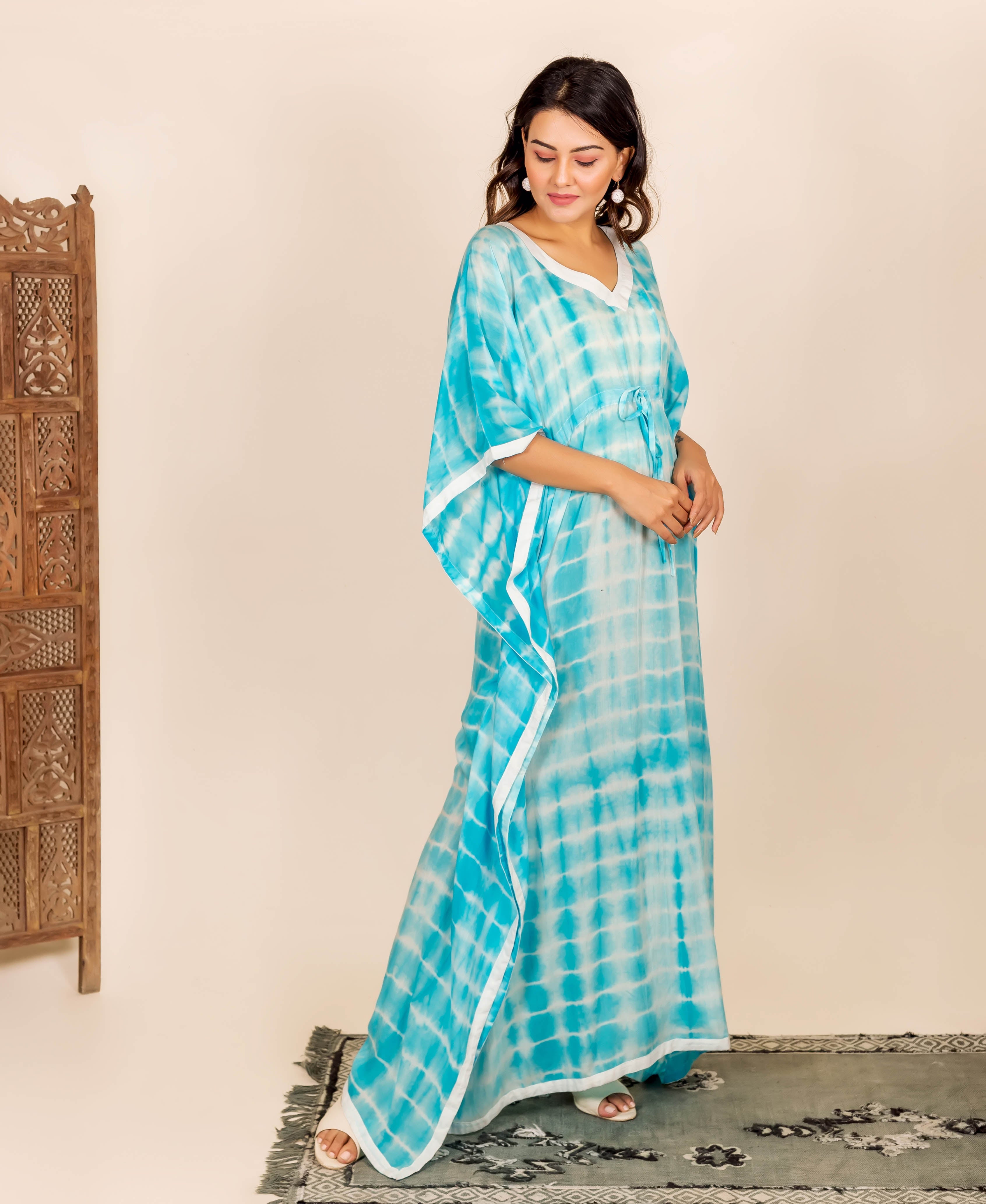 Woman wearing aqua and white tie-dye kaftan with adjustable waist line and white trim.