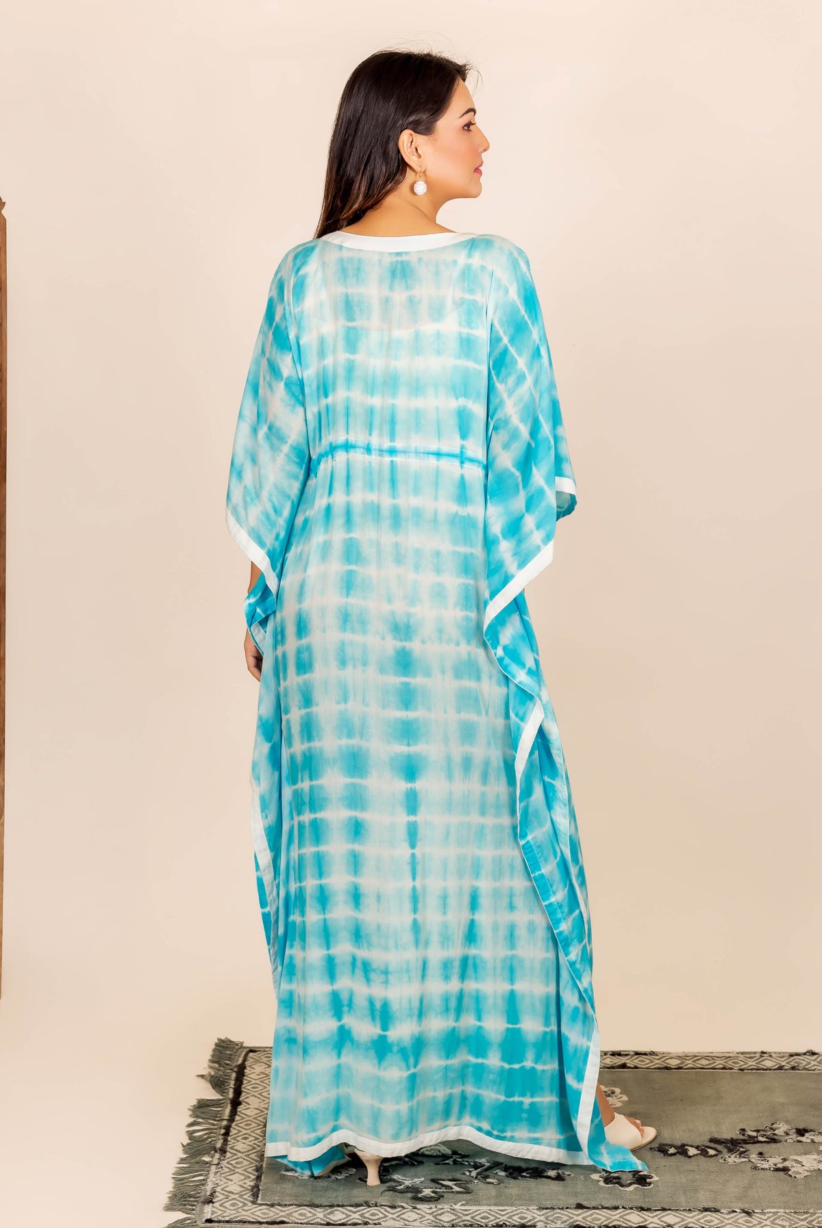 Back view of model in an aqua and white tie-dye full-length kaftan with adjustable waist.