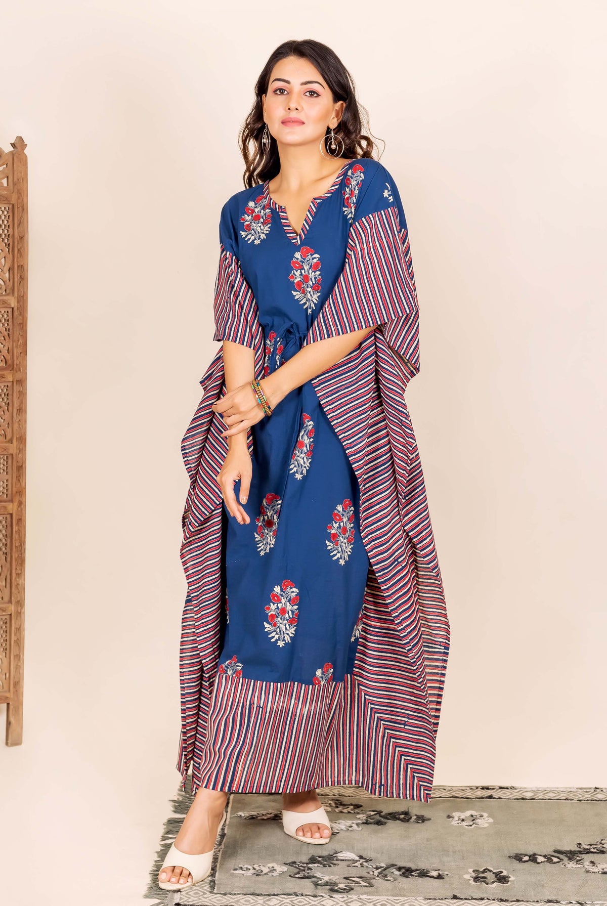 On a model, an indigo kaftan with red floral and striped prints and a tie-up waist.