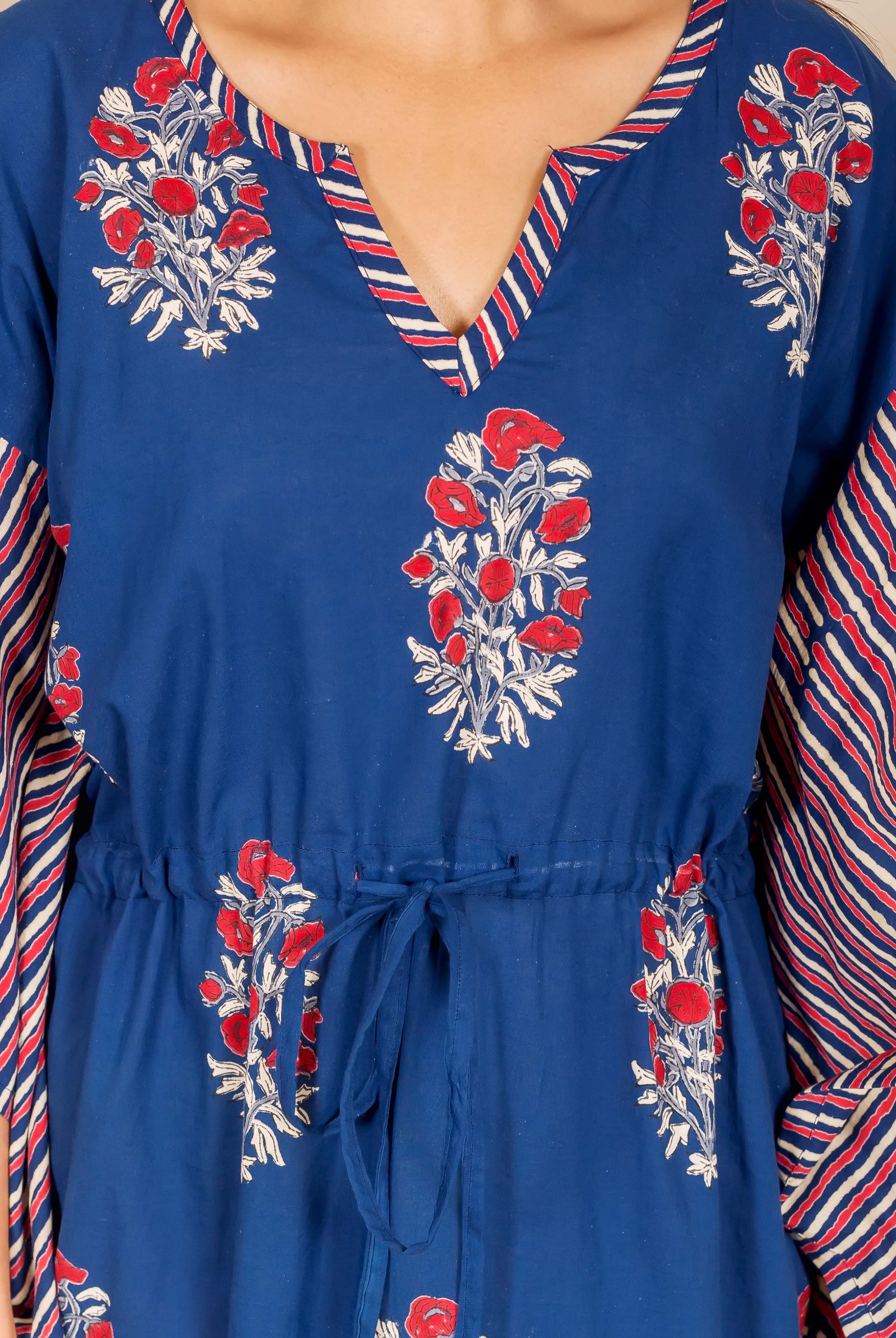 Close-up: model in indigo kaftan with red floral print, striped sleeves, and drawstring.