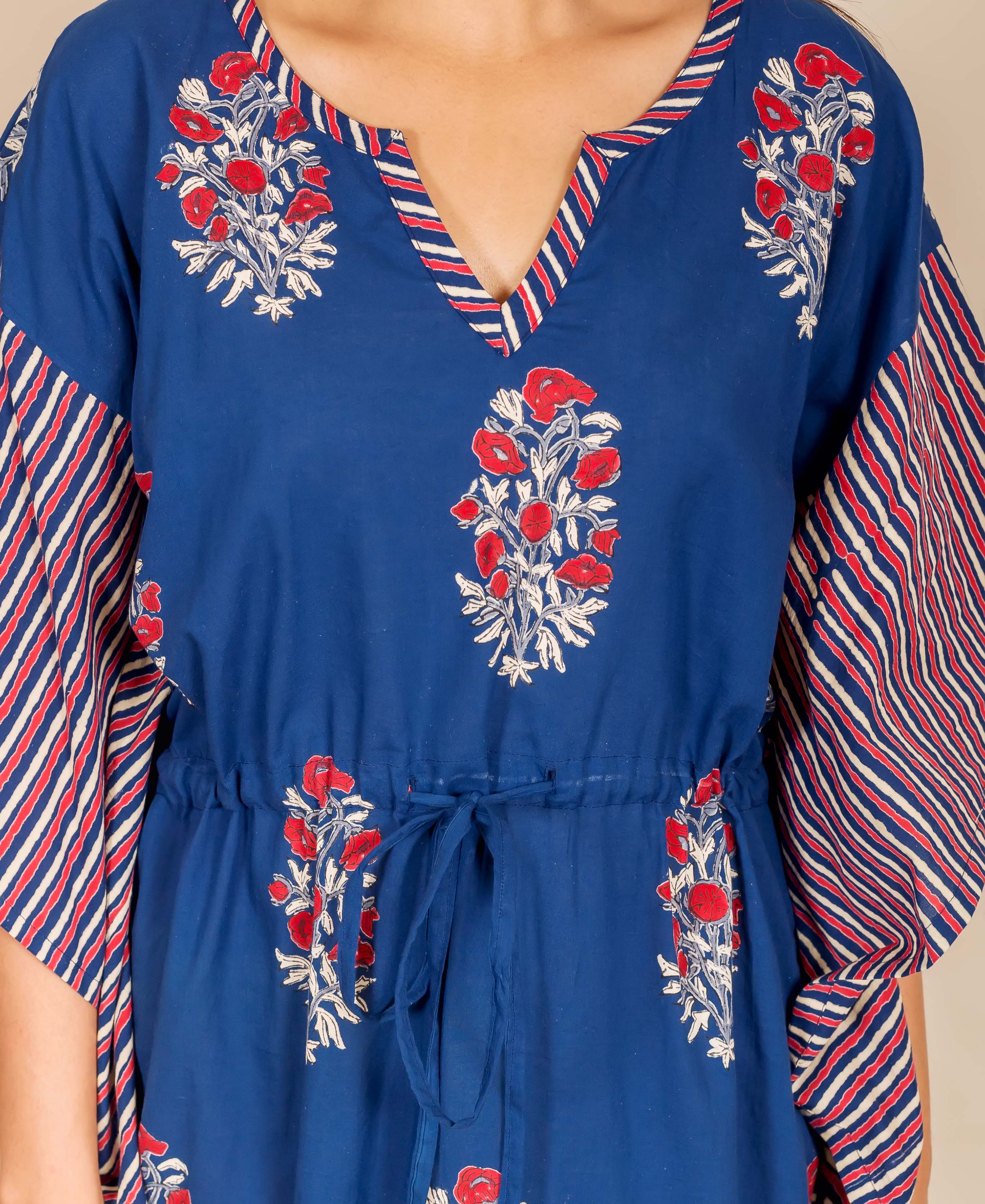 Close-up: model in indigo kaftan with red floral print, striped sleeves, and drawstring.