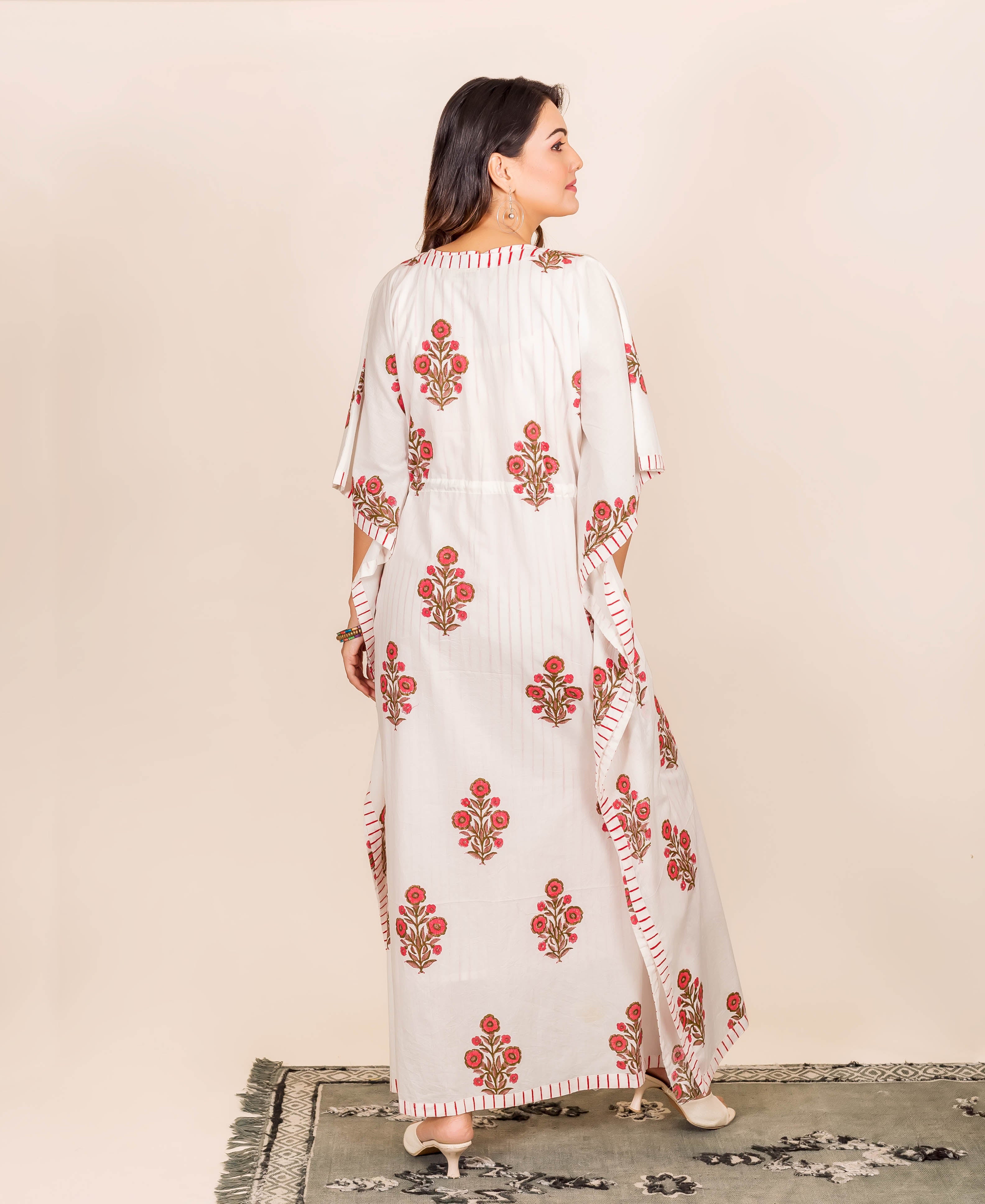 A woman wearing a white kaftan with red floral print.
