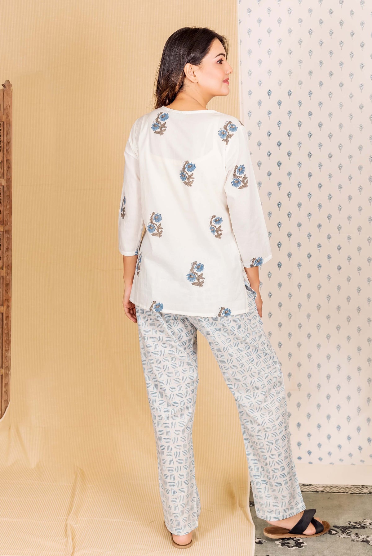 Model from back wearing white hand-block printed lounge wear with blue floral top and geometric pants.