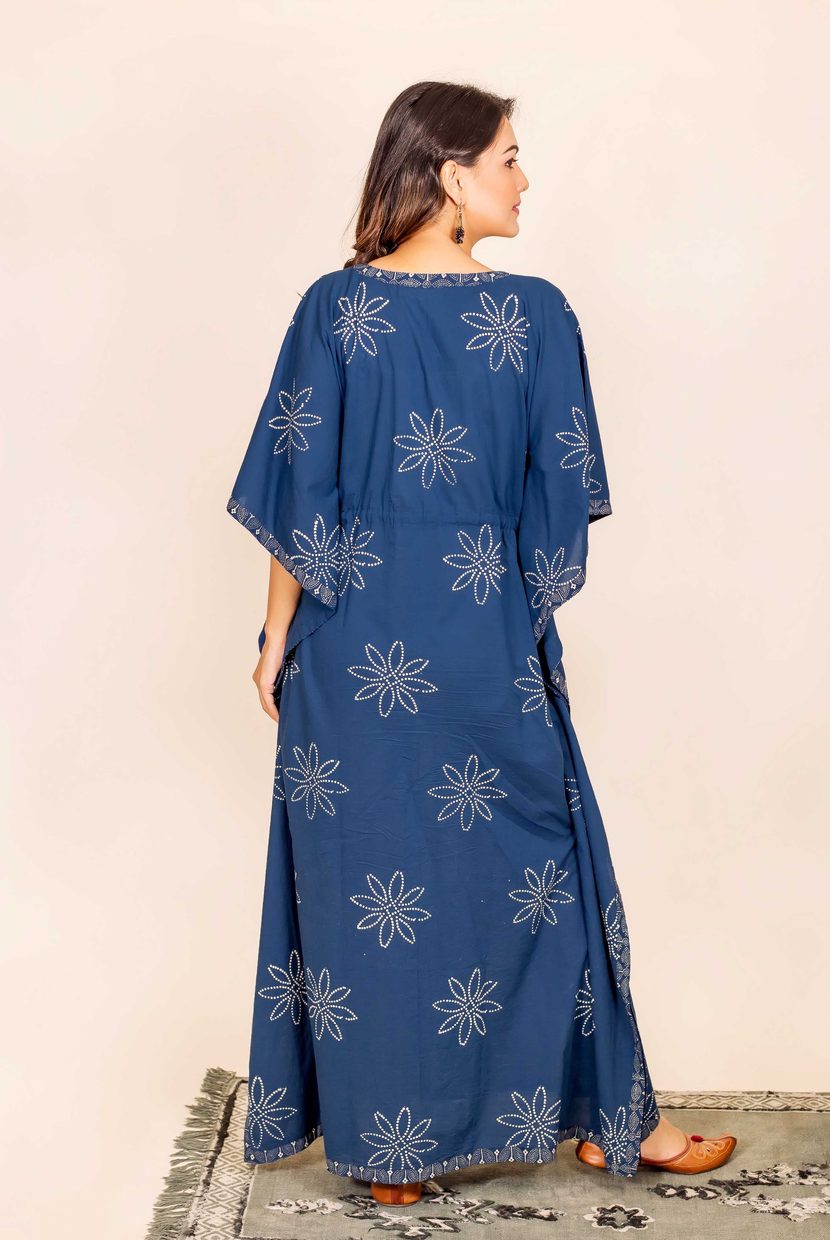Back view of a model wearing a long indigo kaftan with white block-printed star patterns.