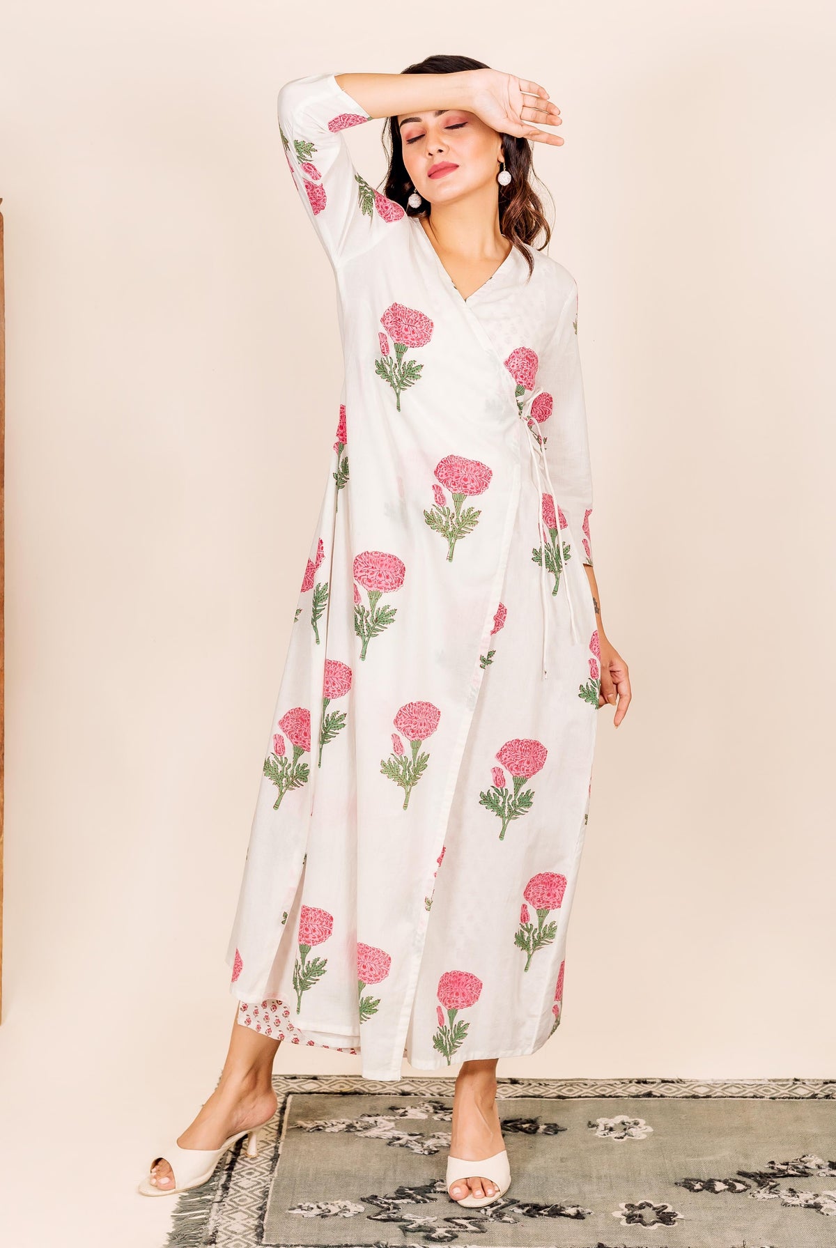 Standing model in a white wrap-style block-printed robe with pink marigold flowers.