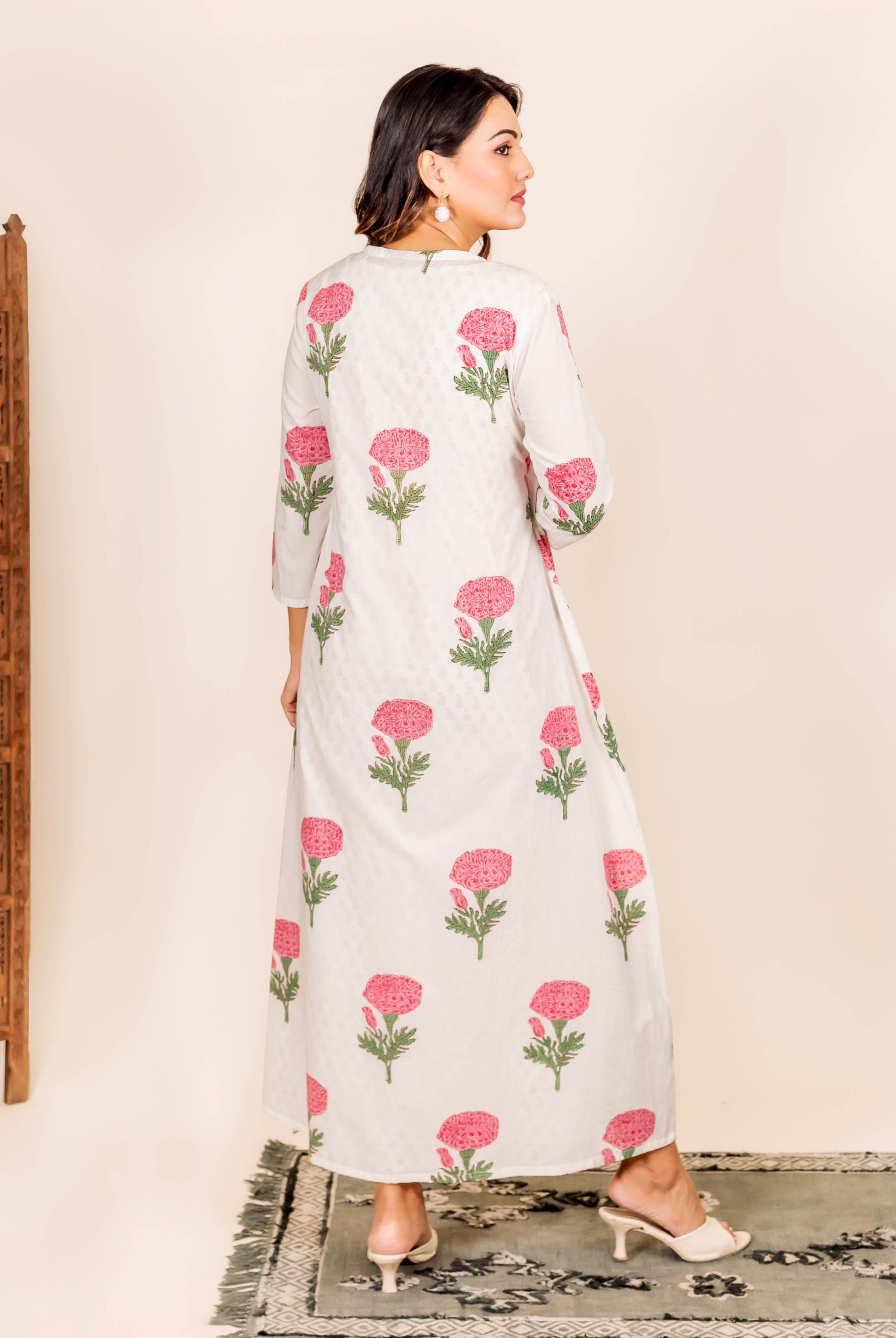 Model in white maxi dress with pink marigold hand-block print, seen from behind.