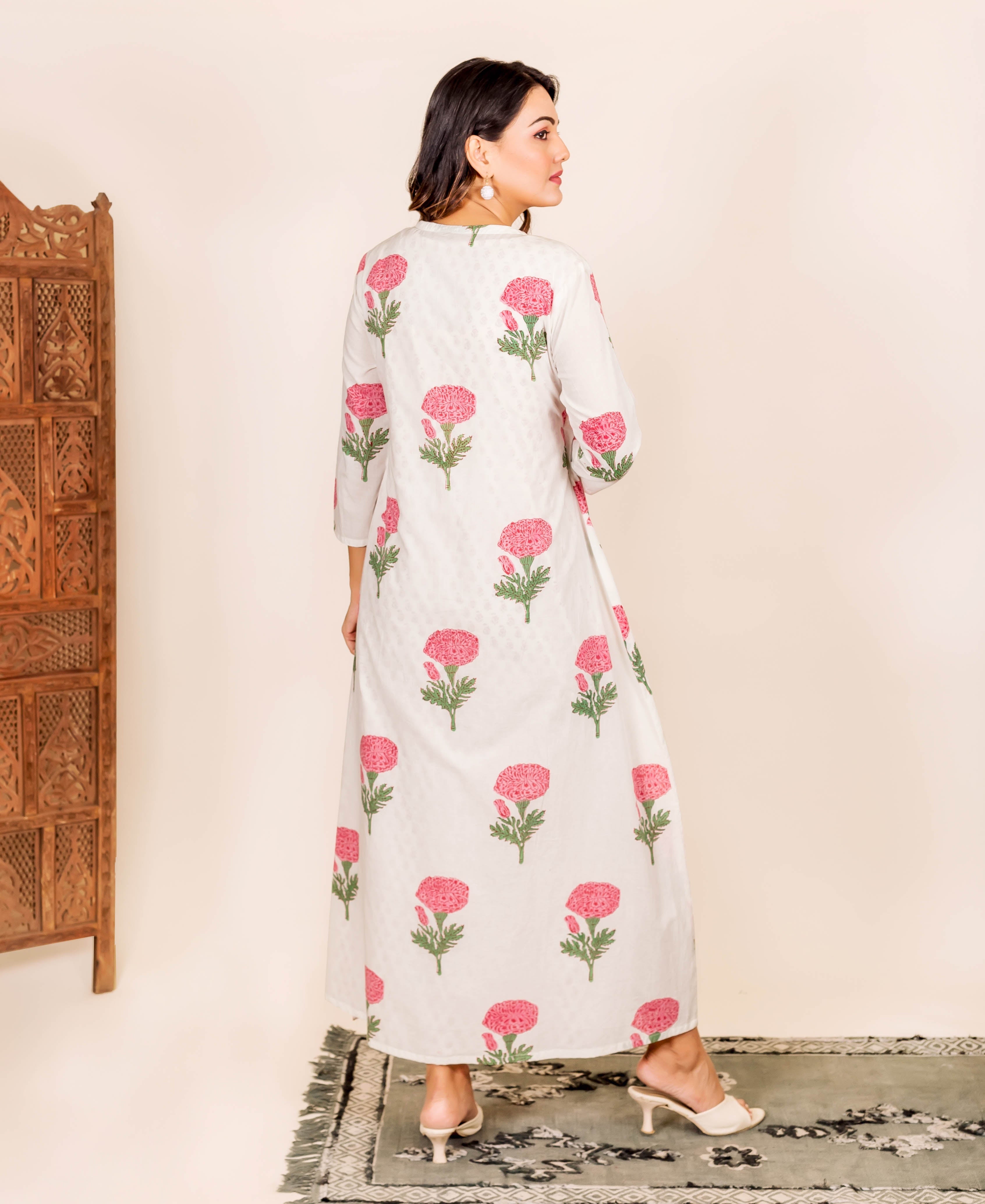 Model in white maxi dress with pink marigold hand-block print, seen from behind.
