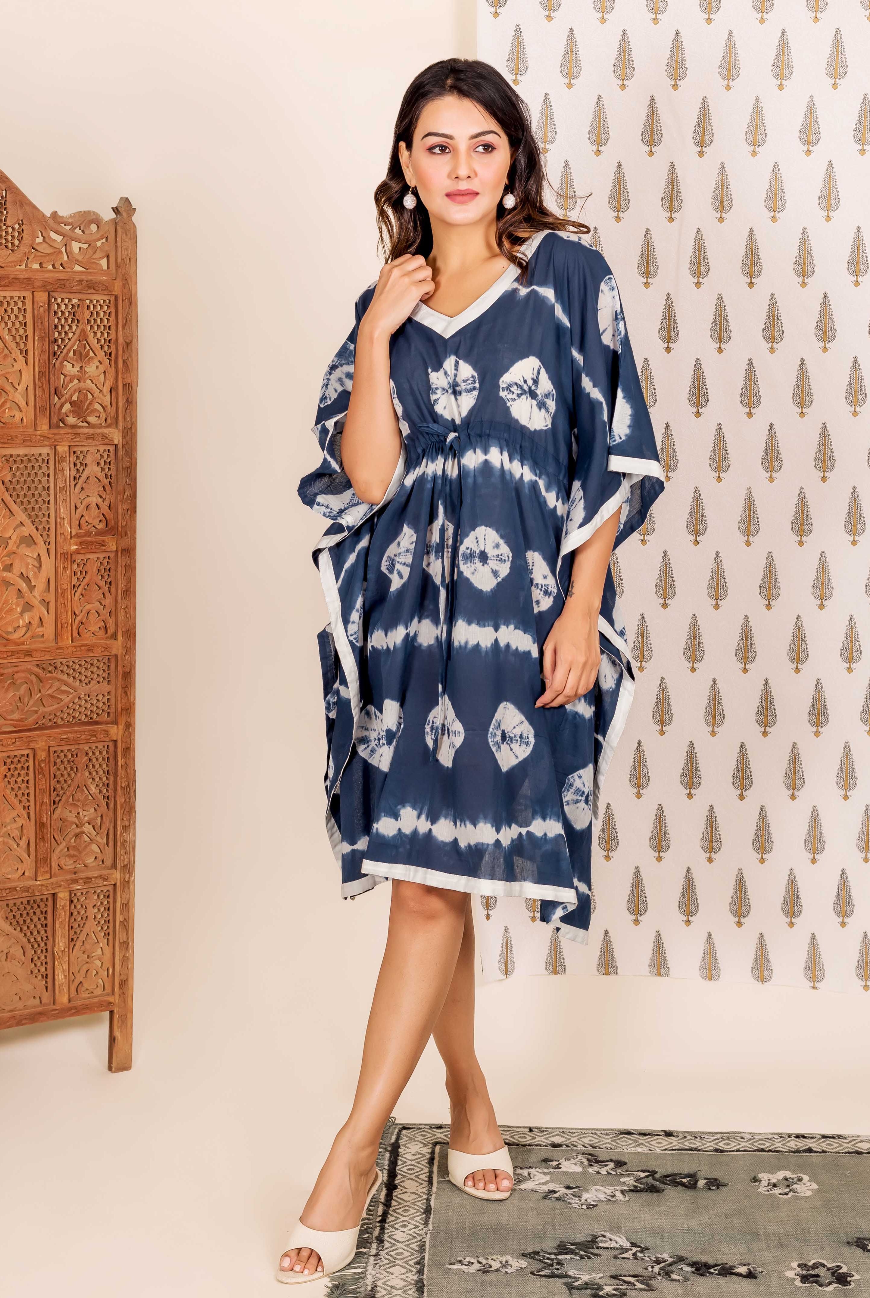 Navy blue kaftan with white tie-dye pattern and trim, on a woman standing indoors.