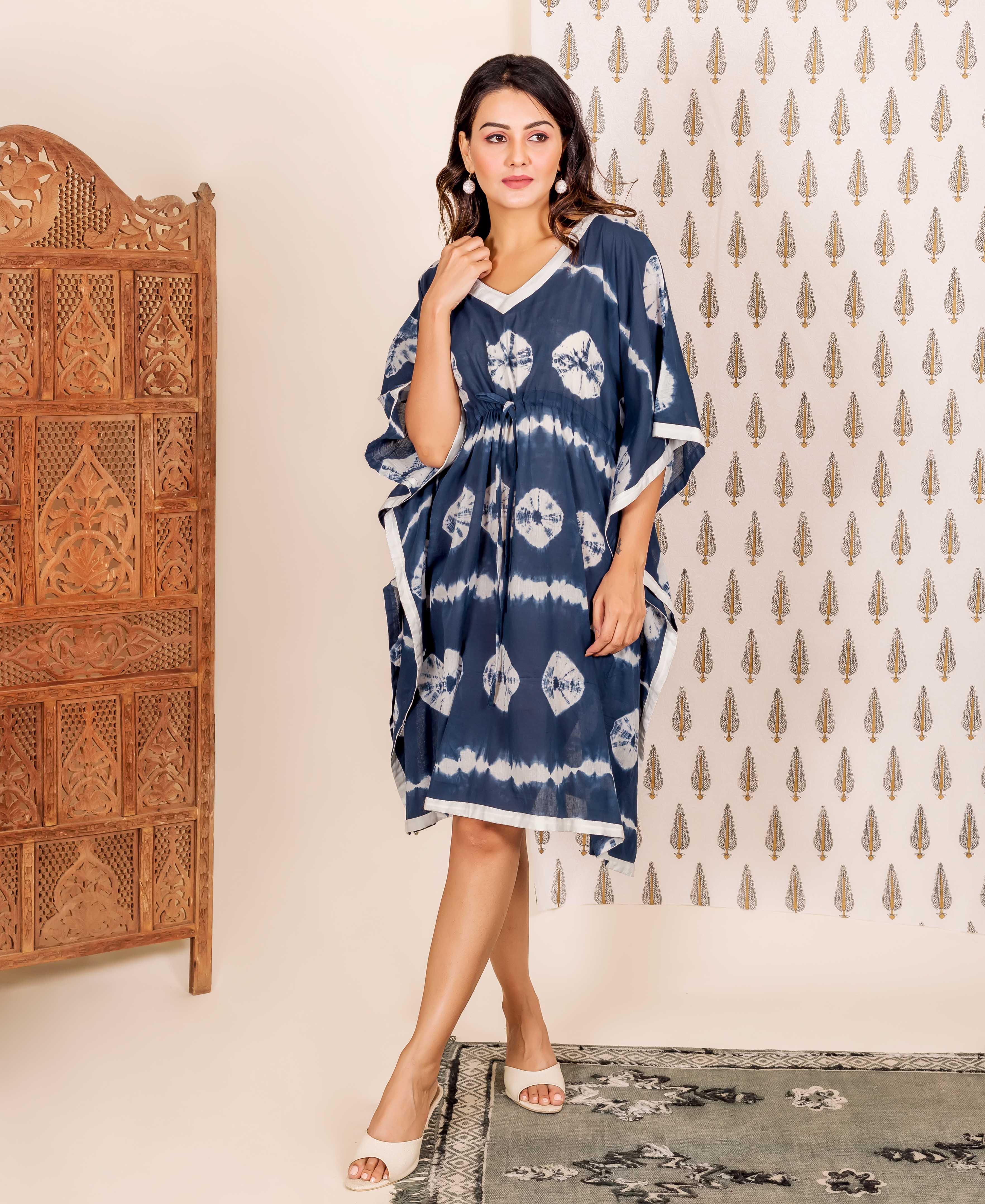 Navy blue kaftan with white tie-dye pattern and trim, on a woman standing indoors.