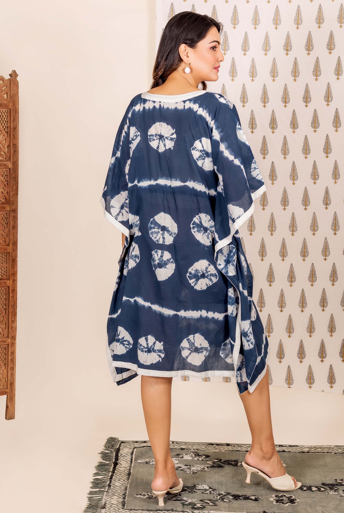Navy blue and white tie-dye kaftan with circular patterns and white trim on a model.