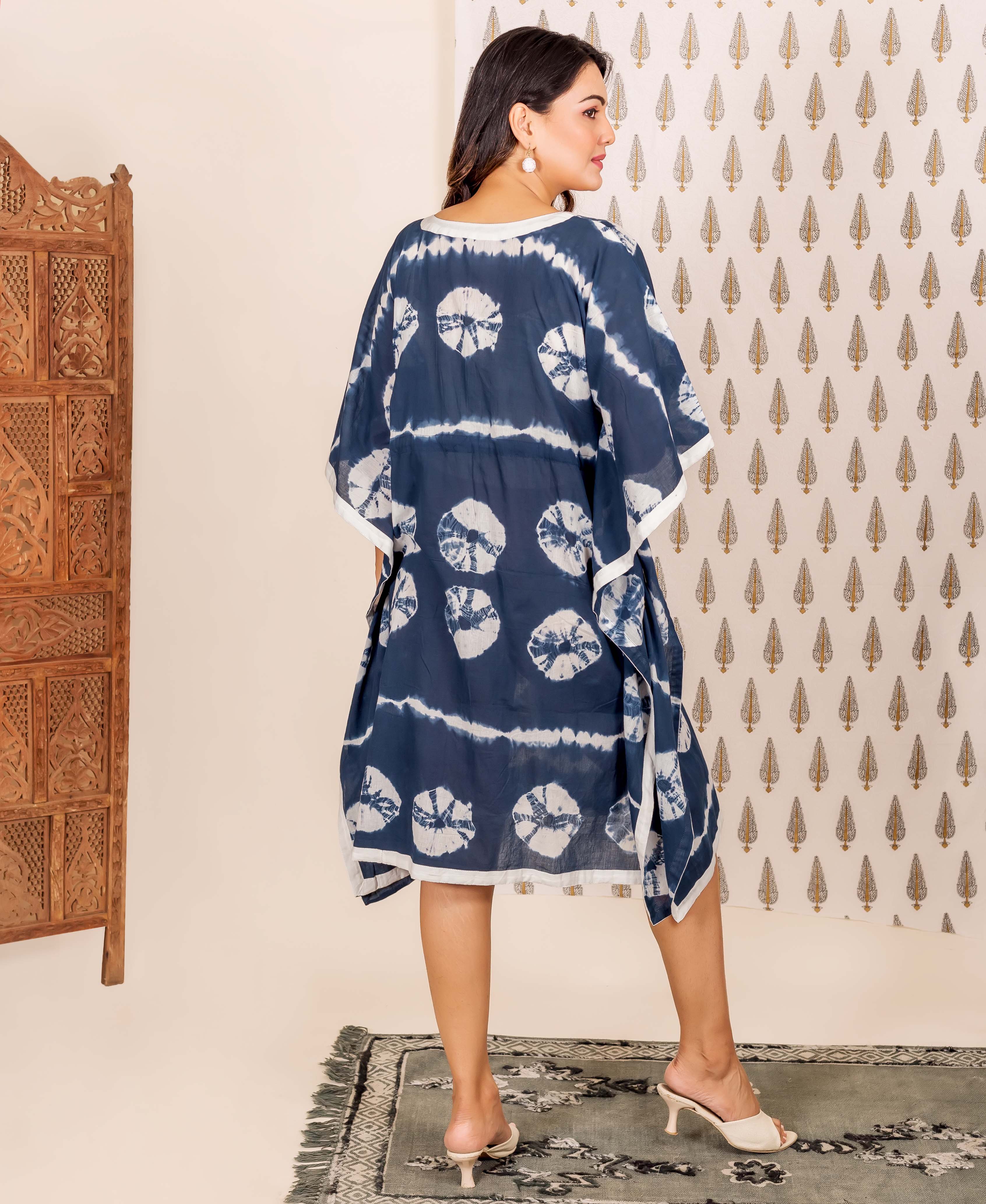 Navy blue and white tie-dye kaftan with circular patterns and white trim on a model.