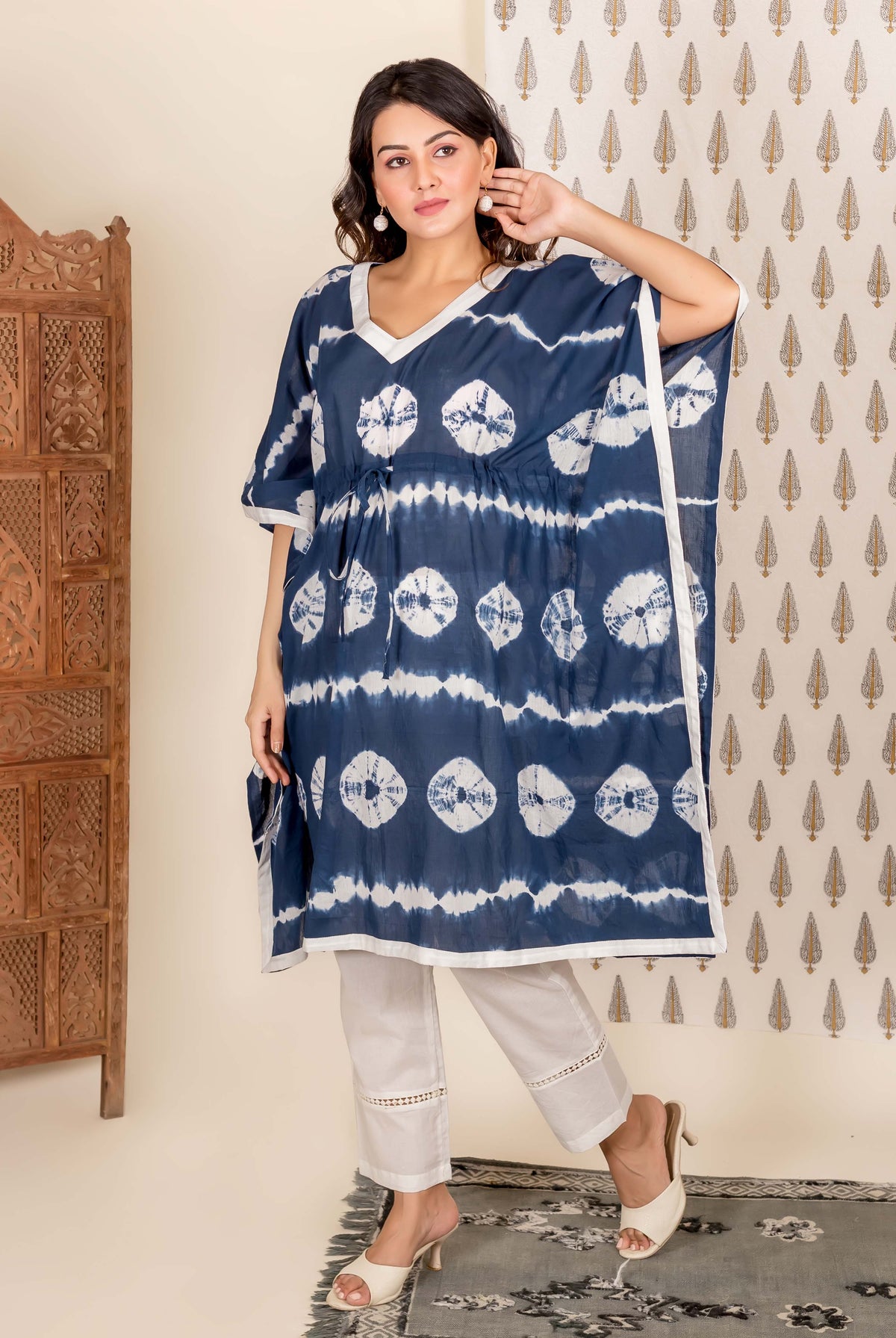 Model wearing navy blue and white tie-dye kaftan and white pants, full front view.