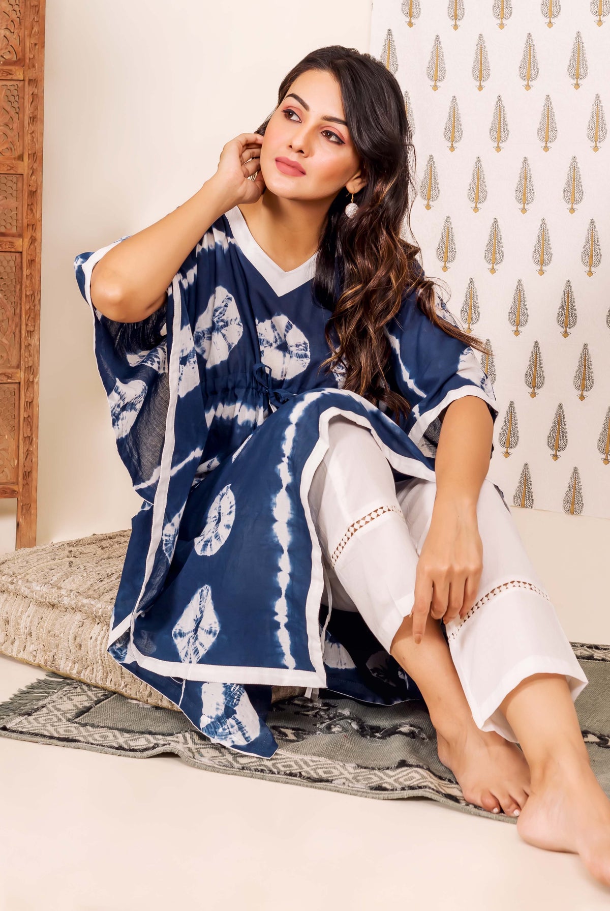 Front view of model wearing a navy blue tie-dye kaftan and white lace pants.