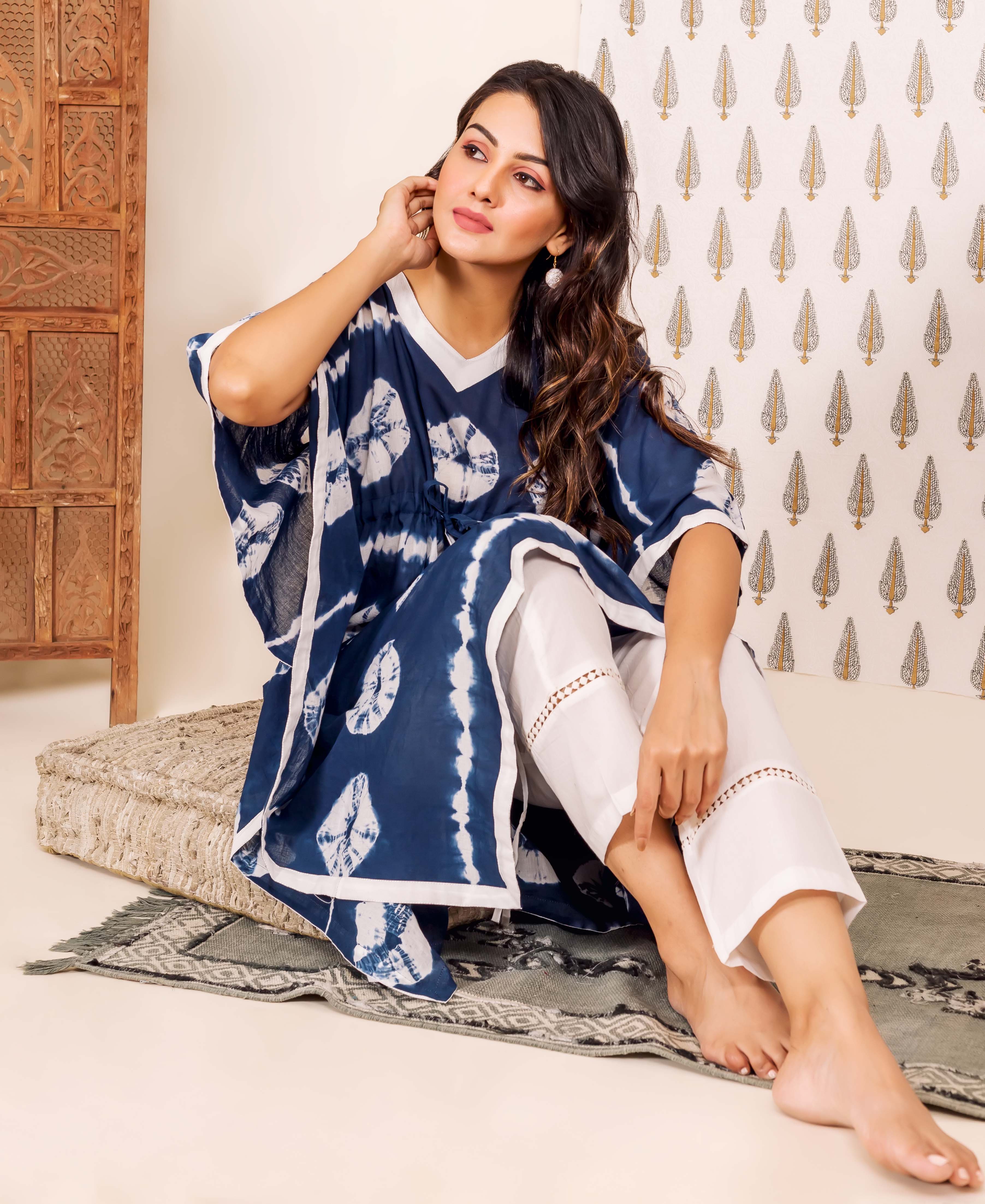Front view of model wearing a navy blue tie-dye kaftan and white lace pants.