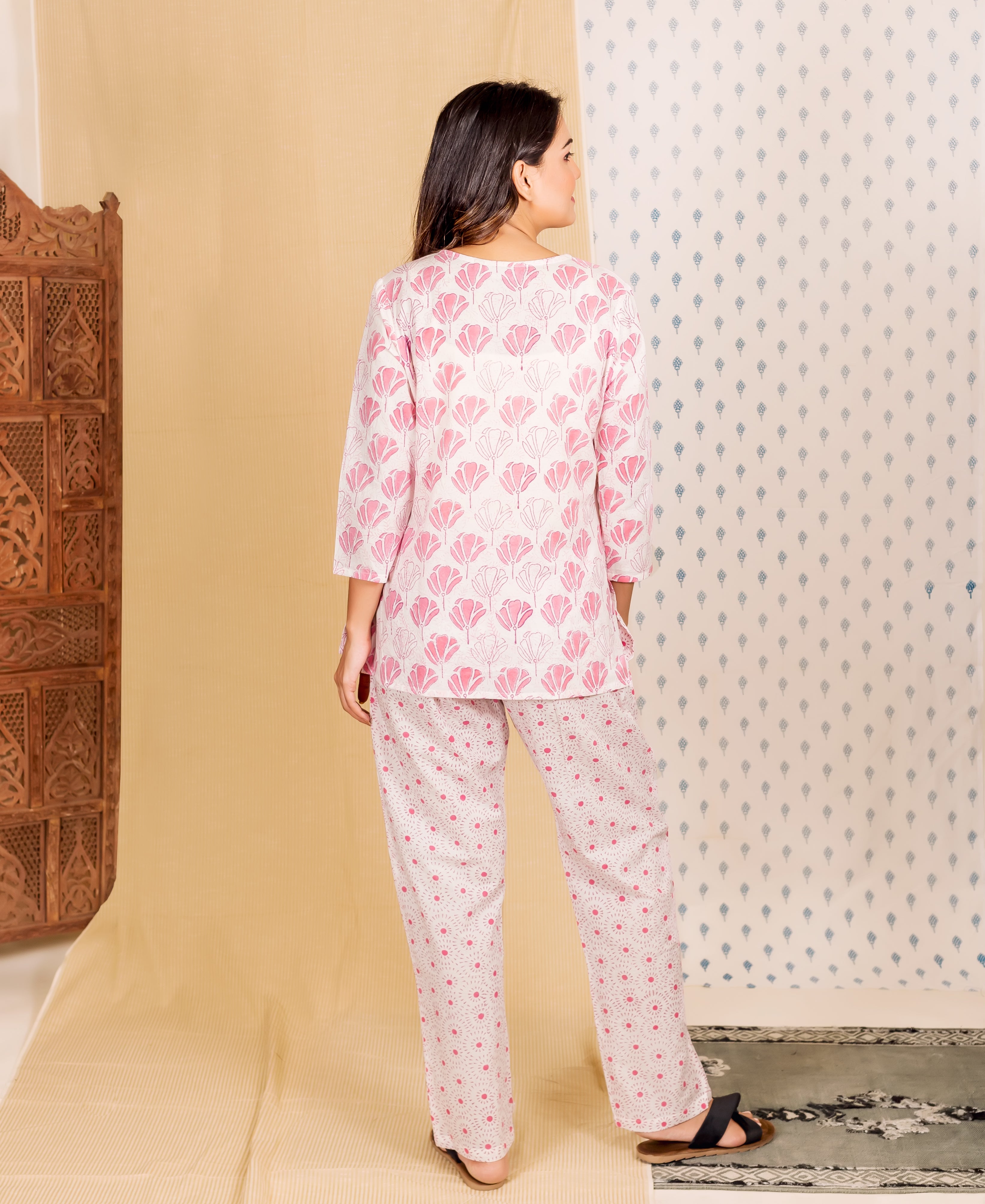Model from back wears a light pink floral pajama top and polka-dot patterned pants.
