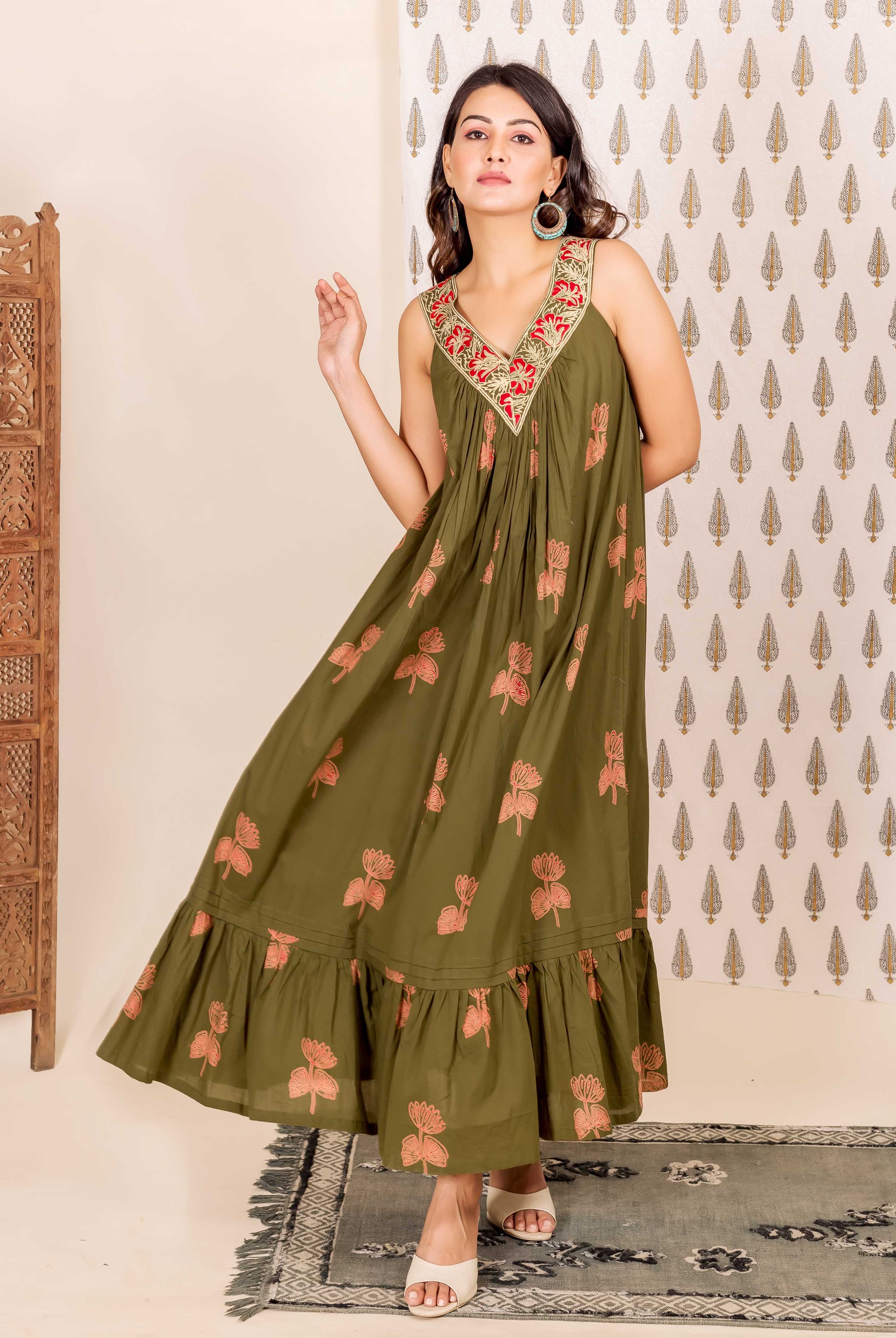 Model wearing olive green sleeveless V-neck dress, red embroidered neckline, peach floral block print.