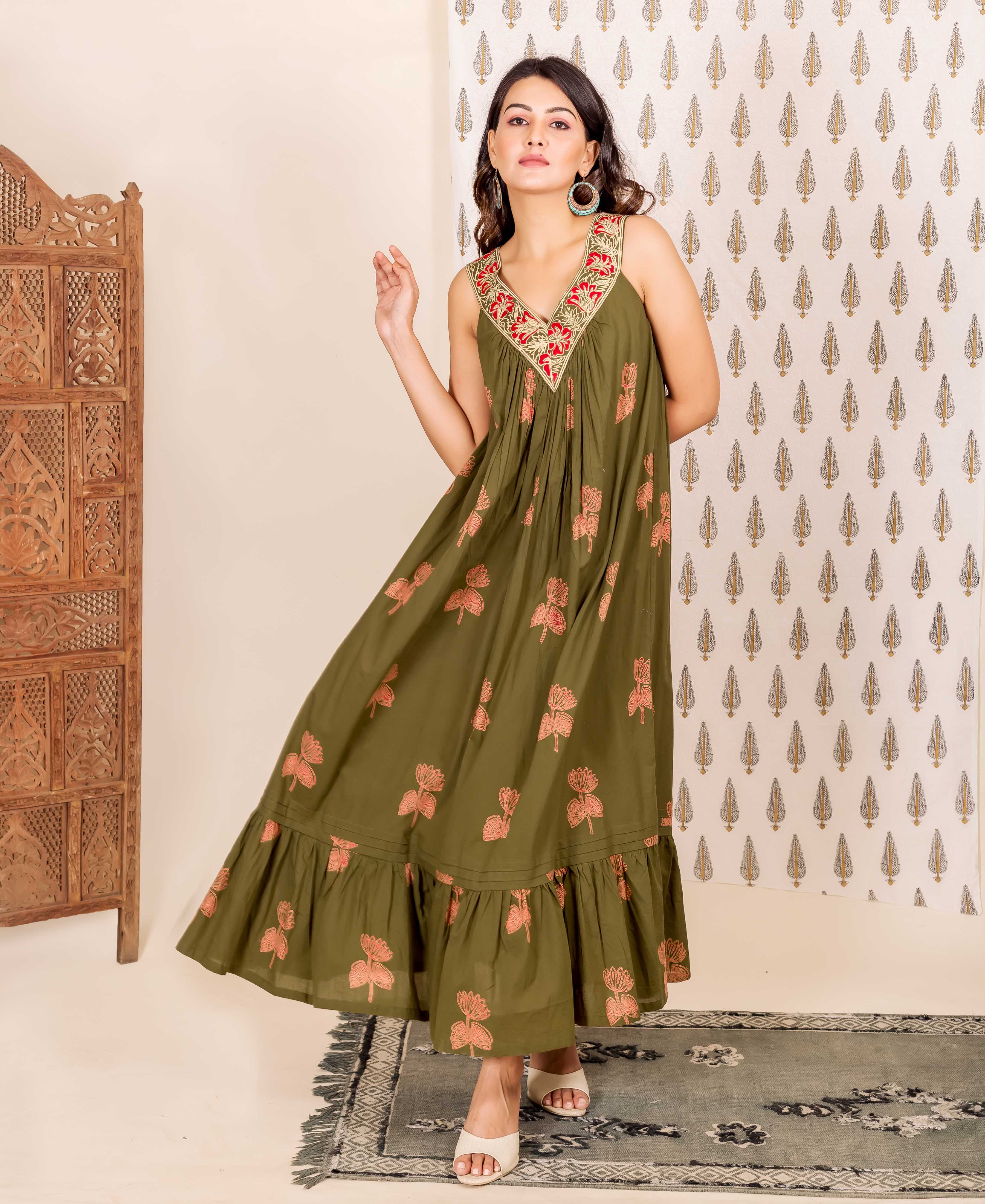 Model wearing olive green sleeveless V-neck dress, red embroidered neckline, peach floral block print.