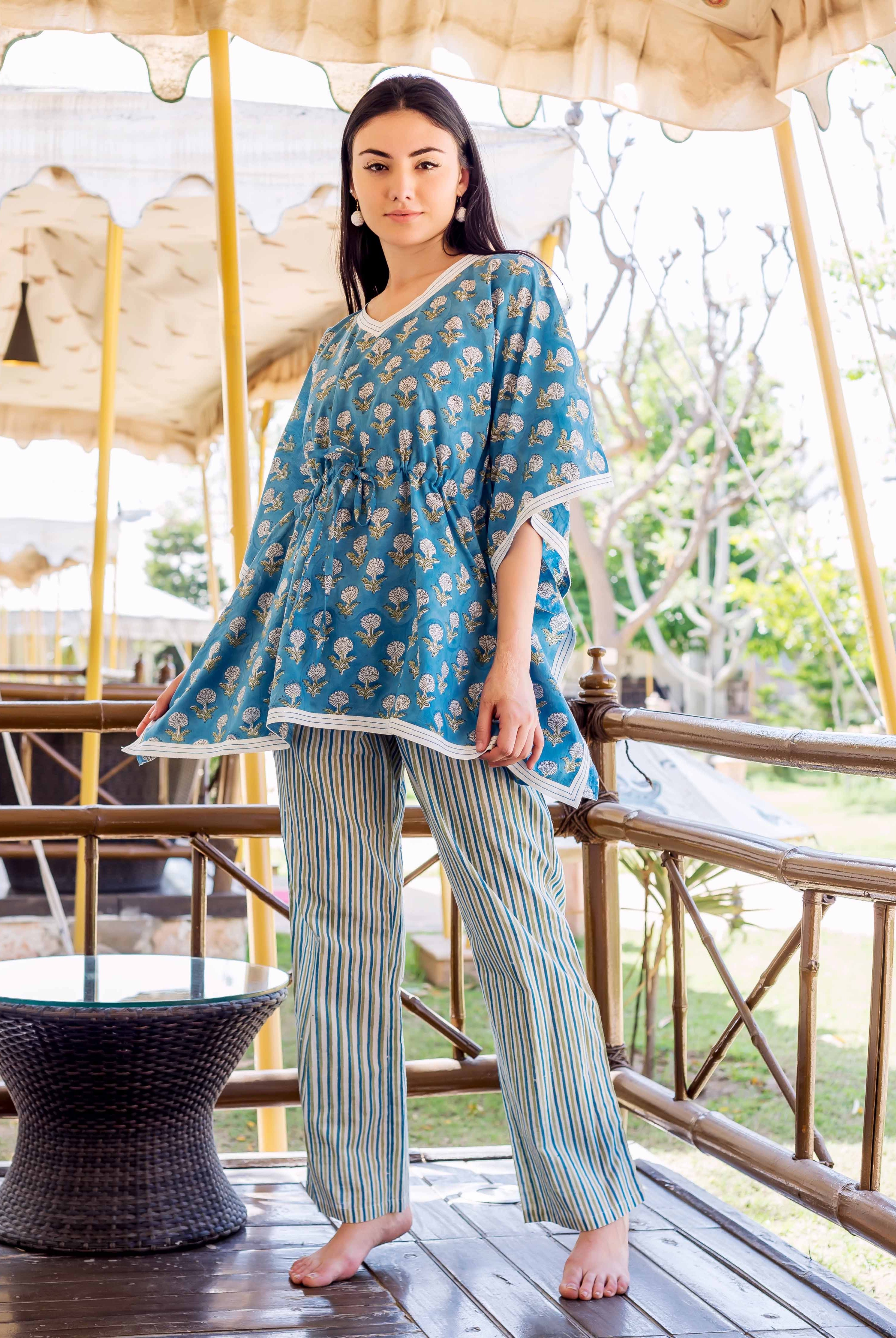 Front full look of model in blue floral hand-block-printed kaftan top and striped trousers.