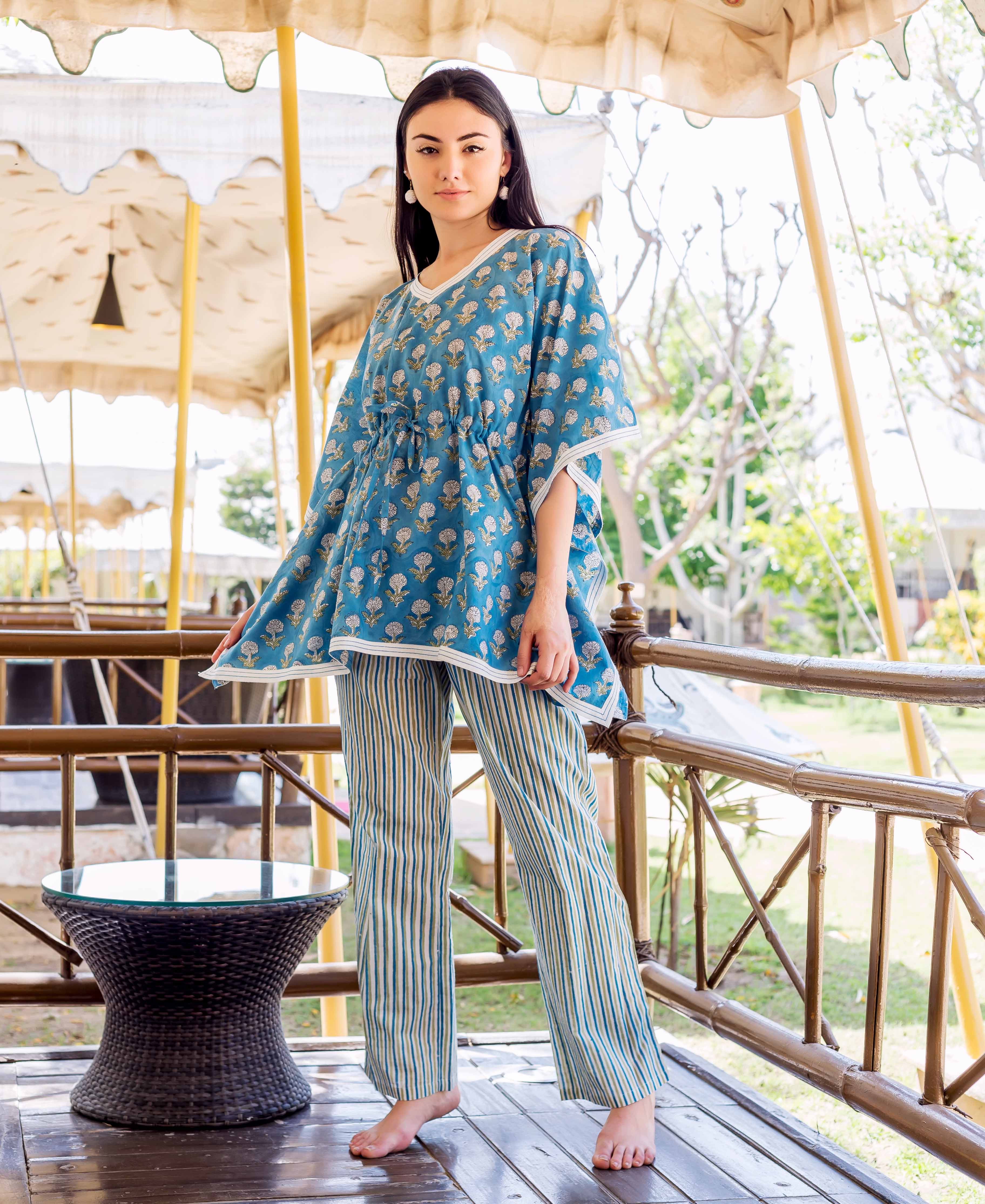 Front full look of model in blue floral hand-block-printed kaftan top and striped trousers.