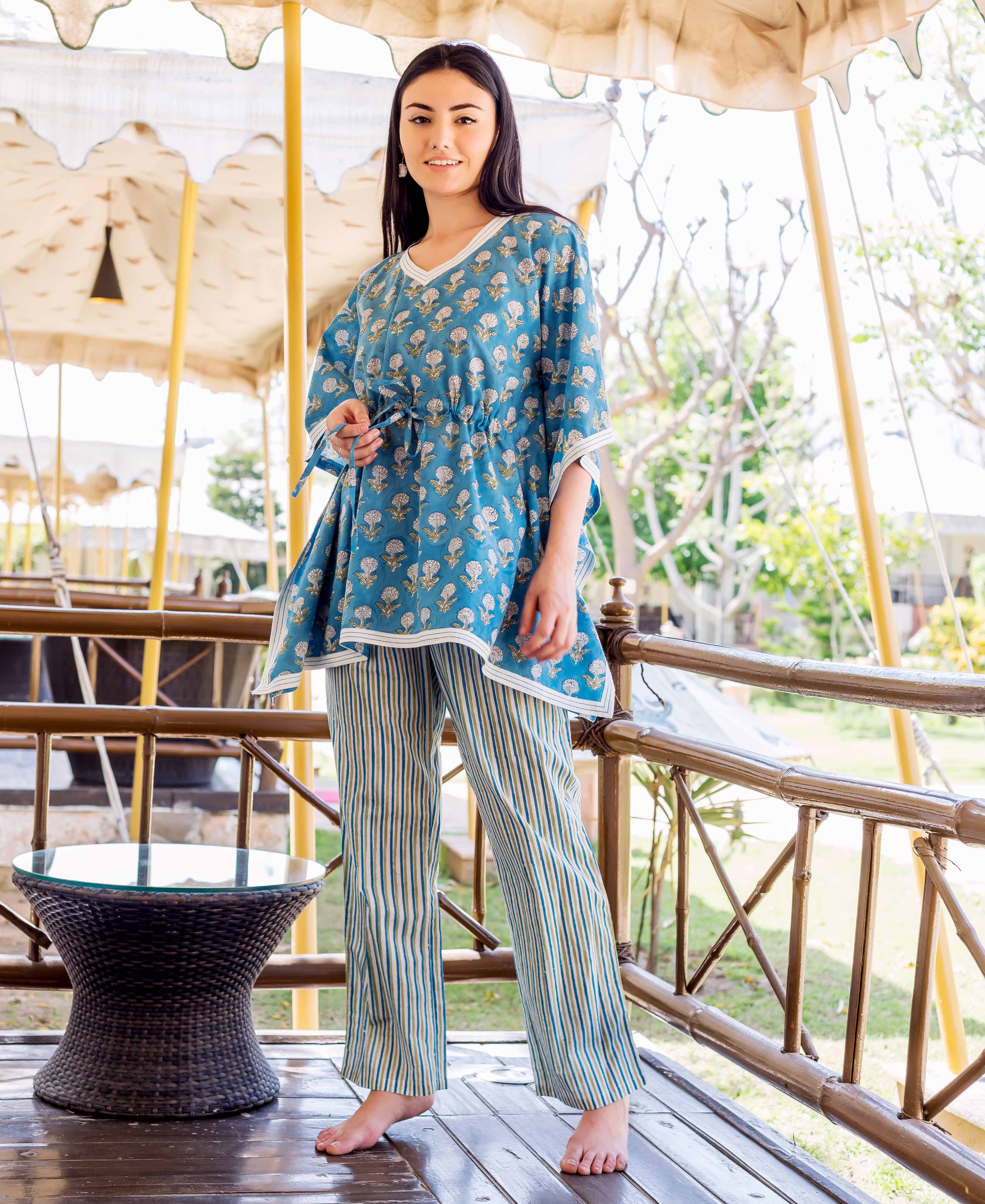 Front view of model in blue floral kaftan top with striped trousers.