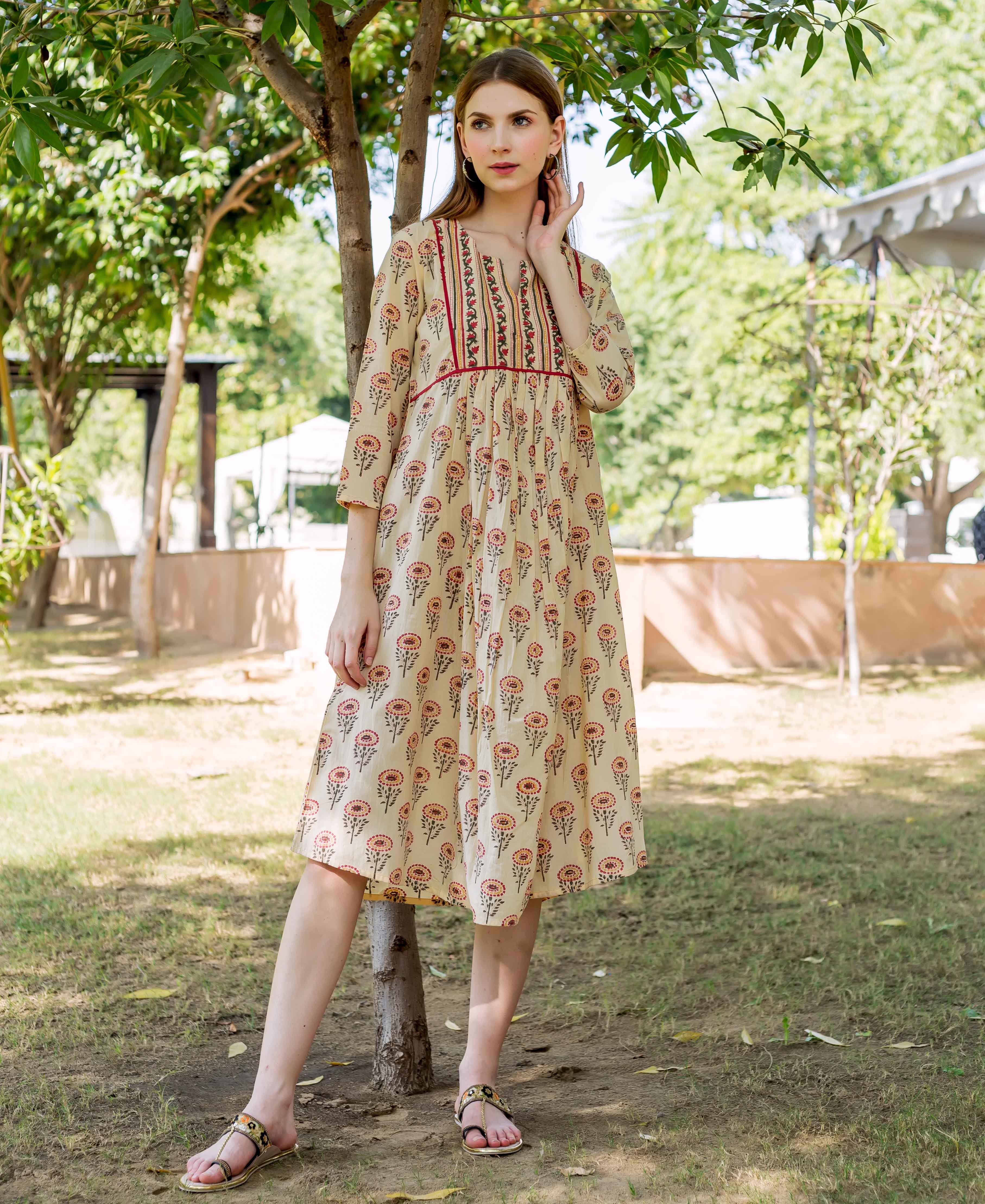 Standing model in a cream hand-block-printed dress with multicolour floral pattern.