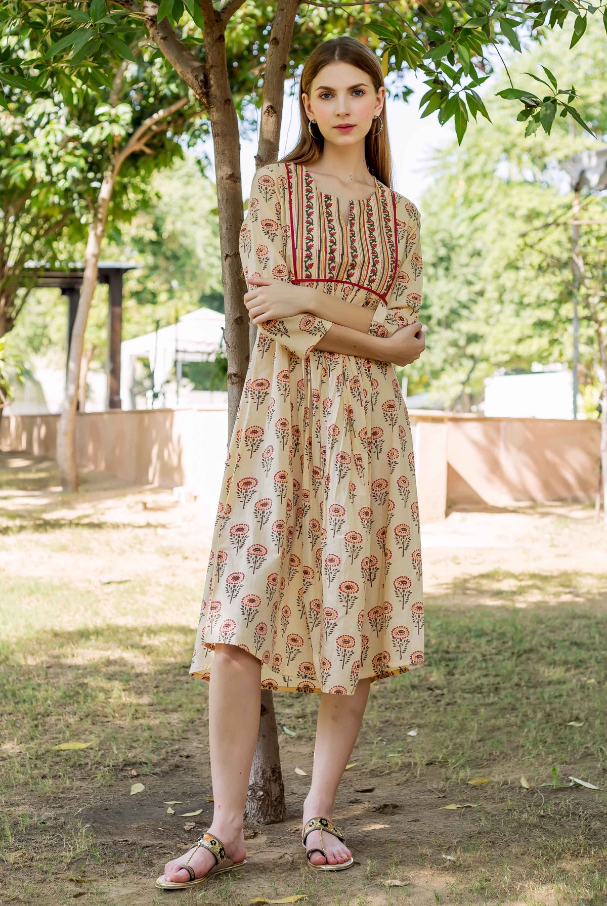 Model in cream hand block printed ethnic dress with red floral and striped patterns.