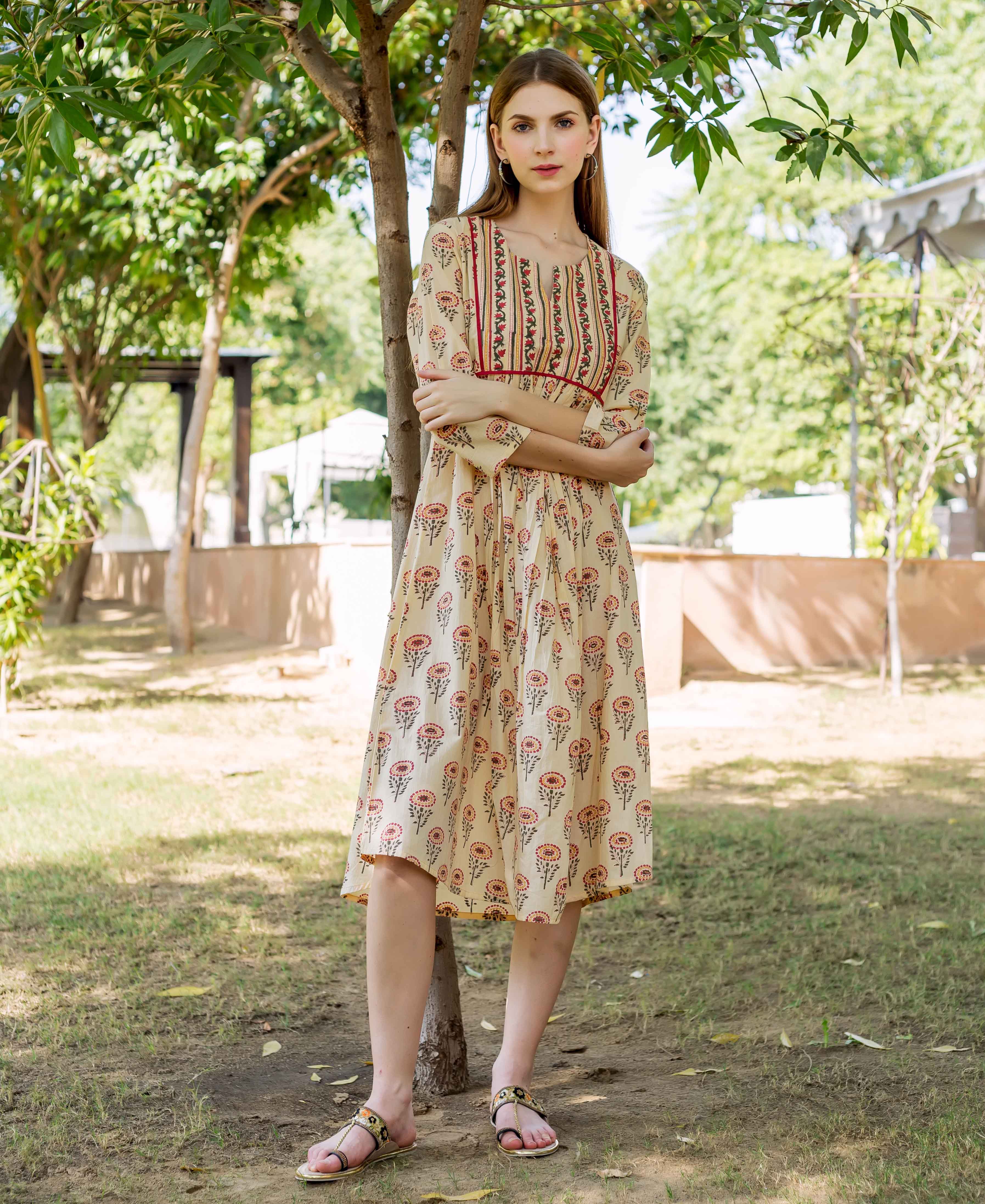 Model in cream hand block printed ethnic dress with red floral and striped patterns.