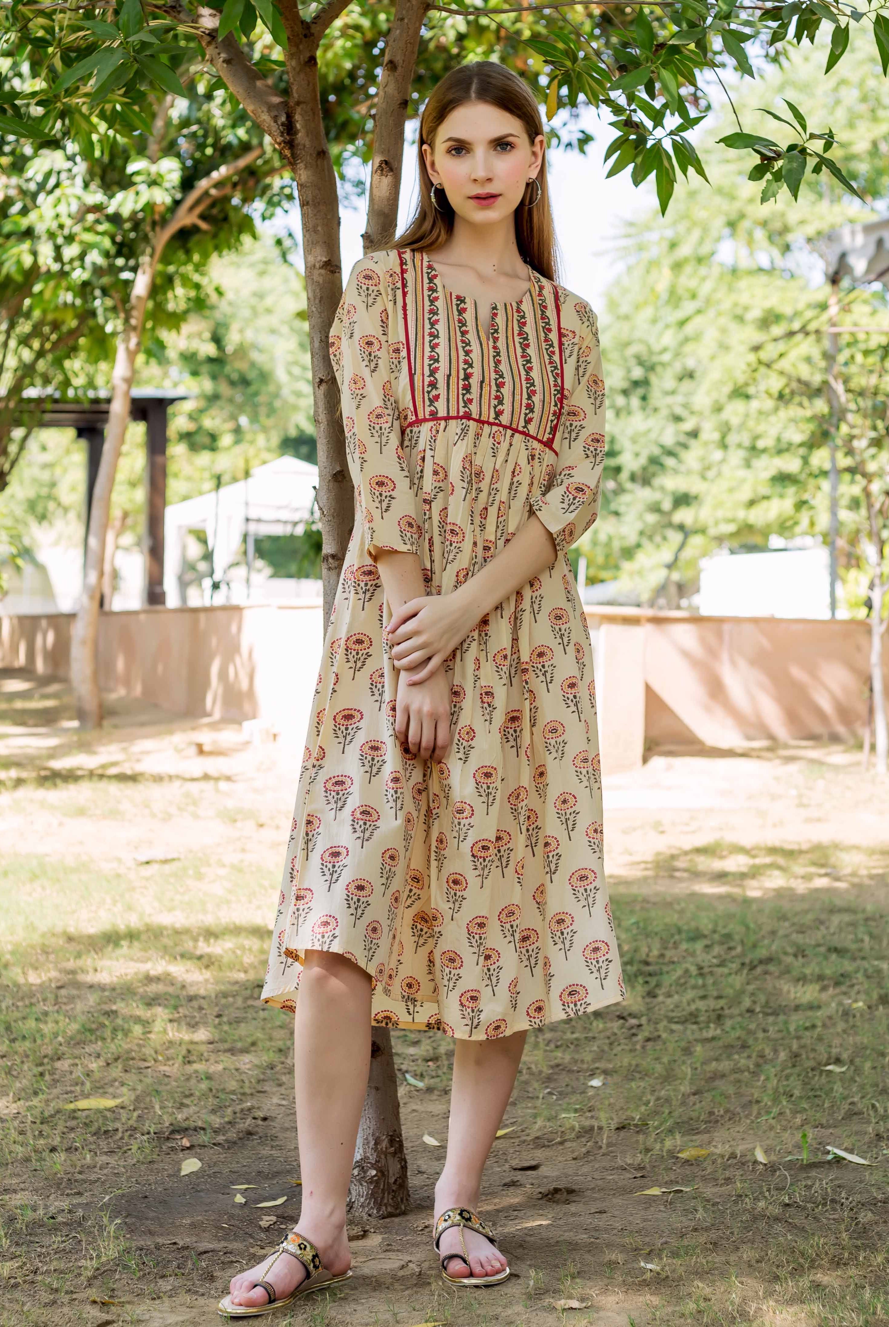 Model wearing a beige hand-block printed midi dress with colorful floral and stripe patterns.