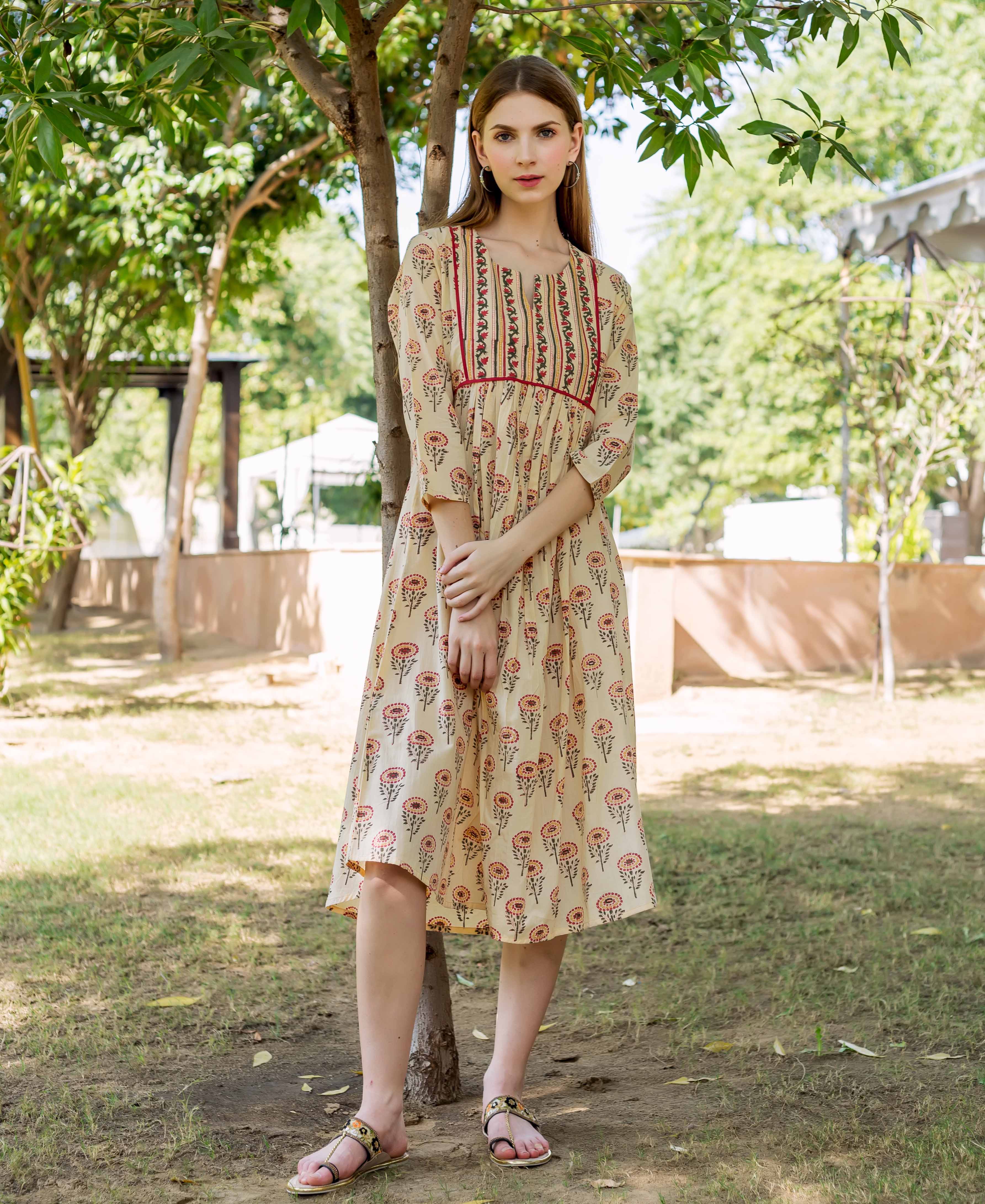 Model wearing a beige hand-block printed midi dress with colorful floral and stripe patterns.