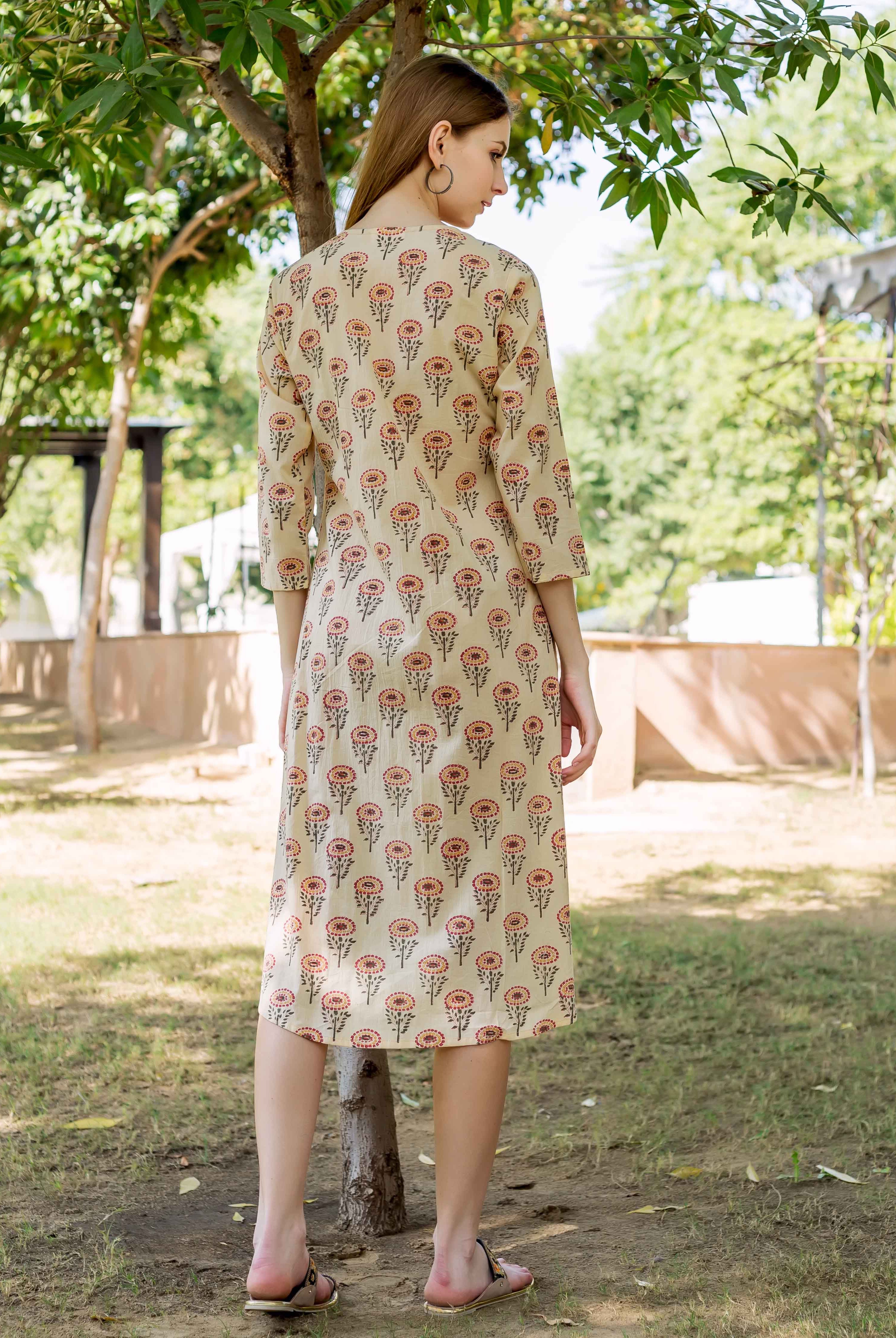Model from back wearing a cream midi dress with red and brown floral hand-block print.