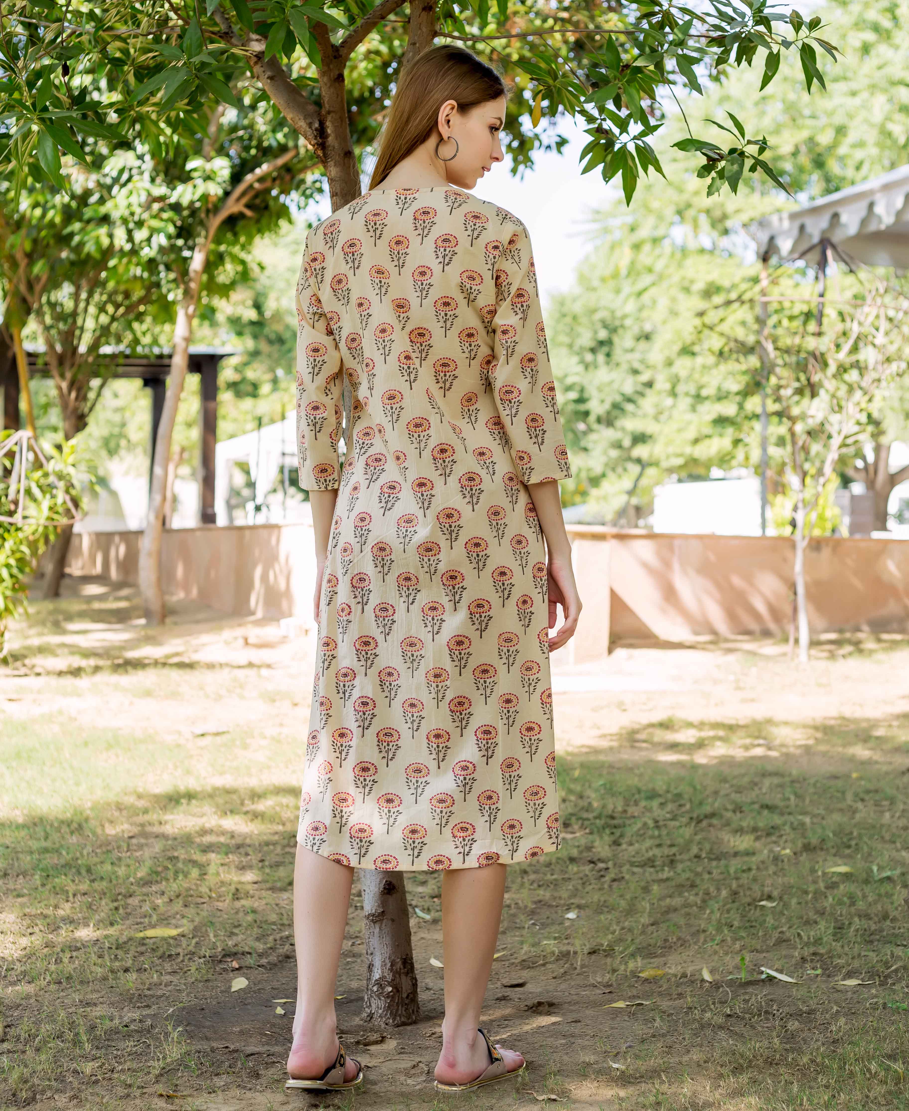Model from back wearing a cream midi dress with red and brown floral hand-block print.