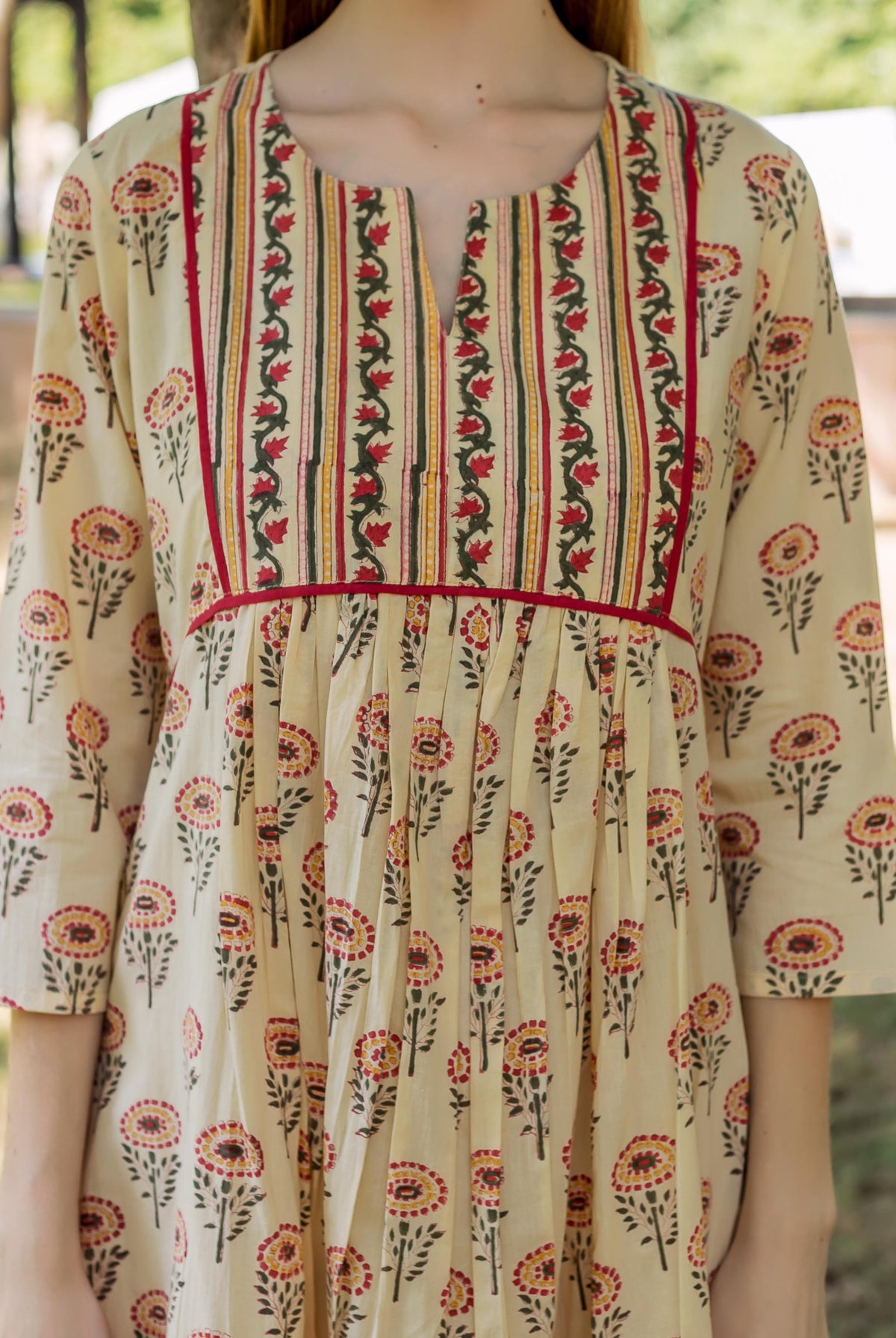 Light yellow hand-block printed dress with a patterned bodice, pleated skirt, and multi-color floral print.