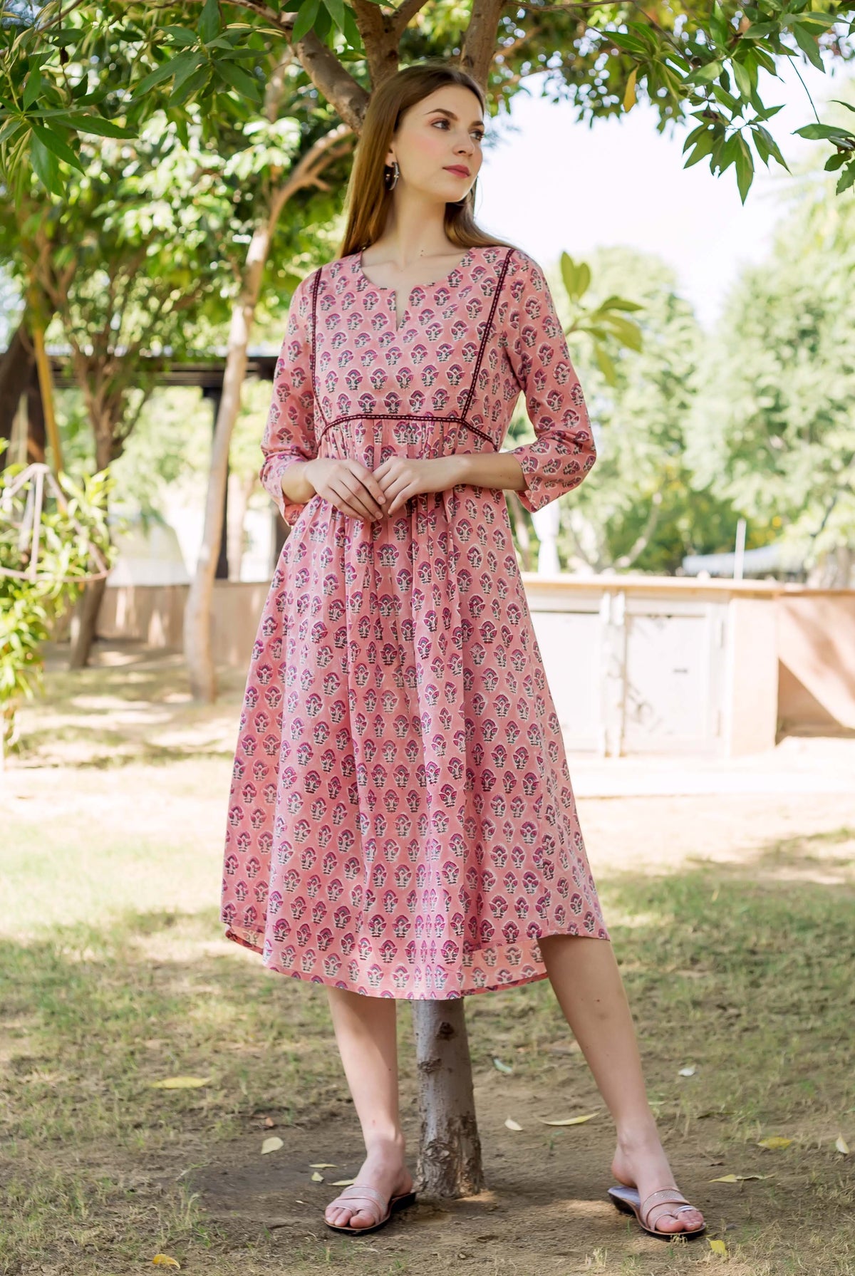 A model wearing a peach hand-block-printed dress with a floral pattern.