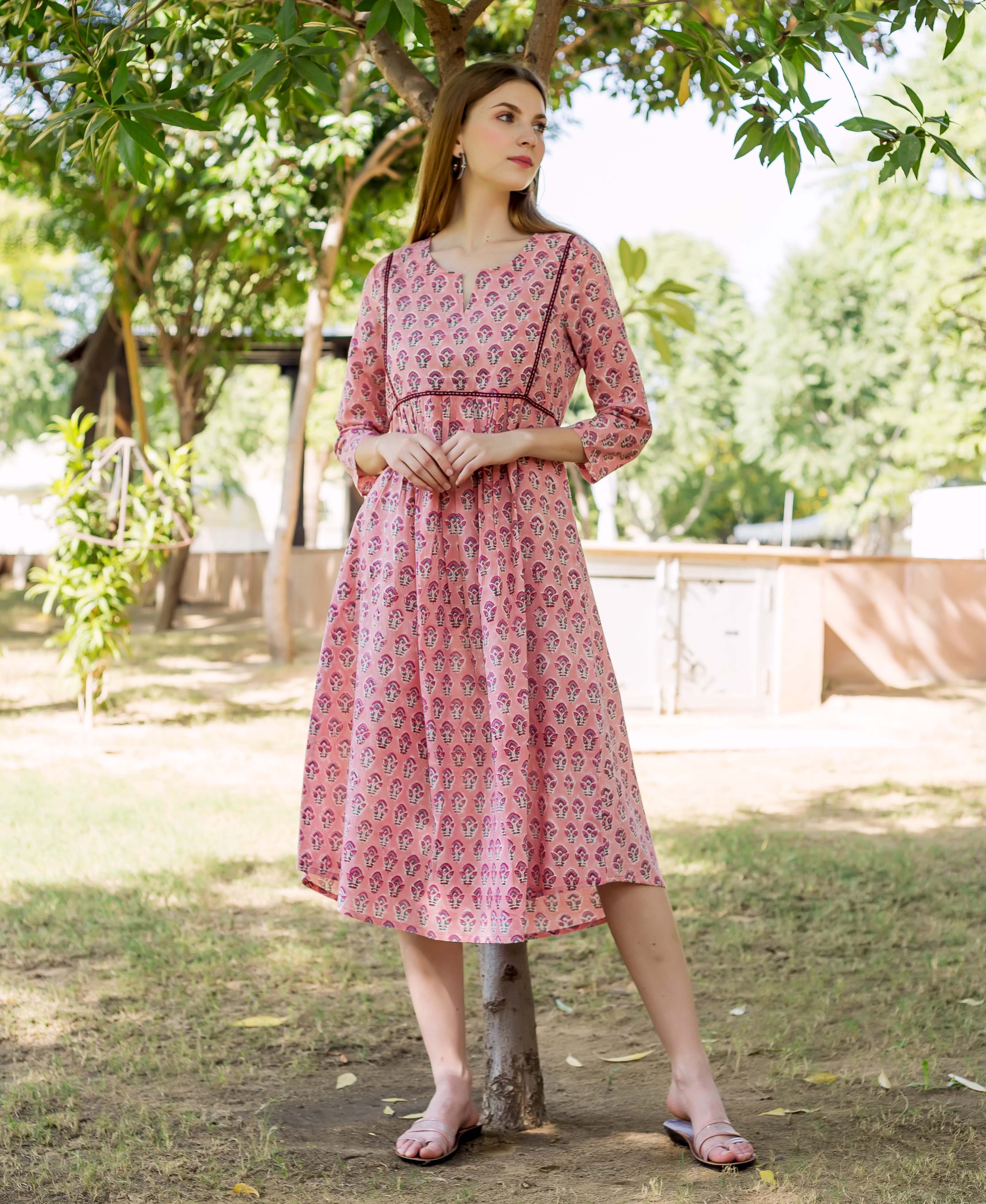 A model wearing a peach hand-block-printed dress with a floral pattern.