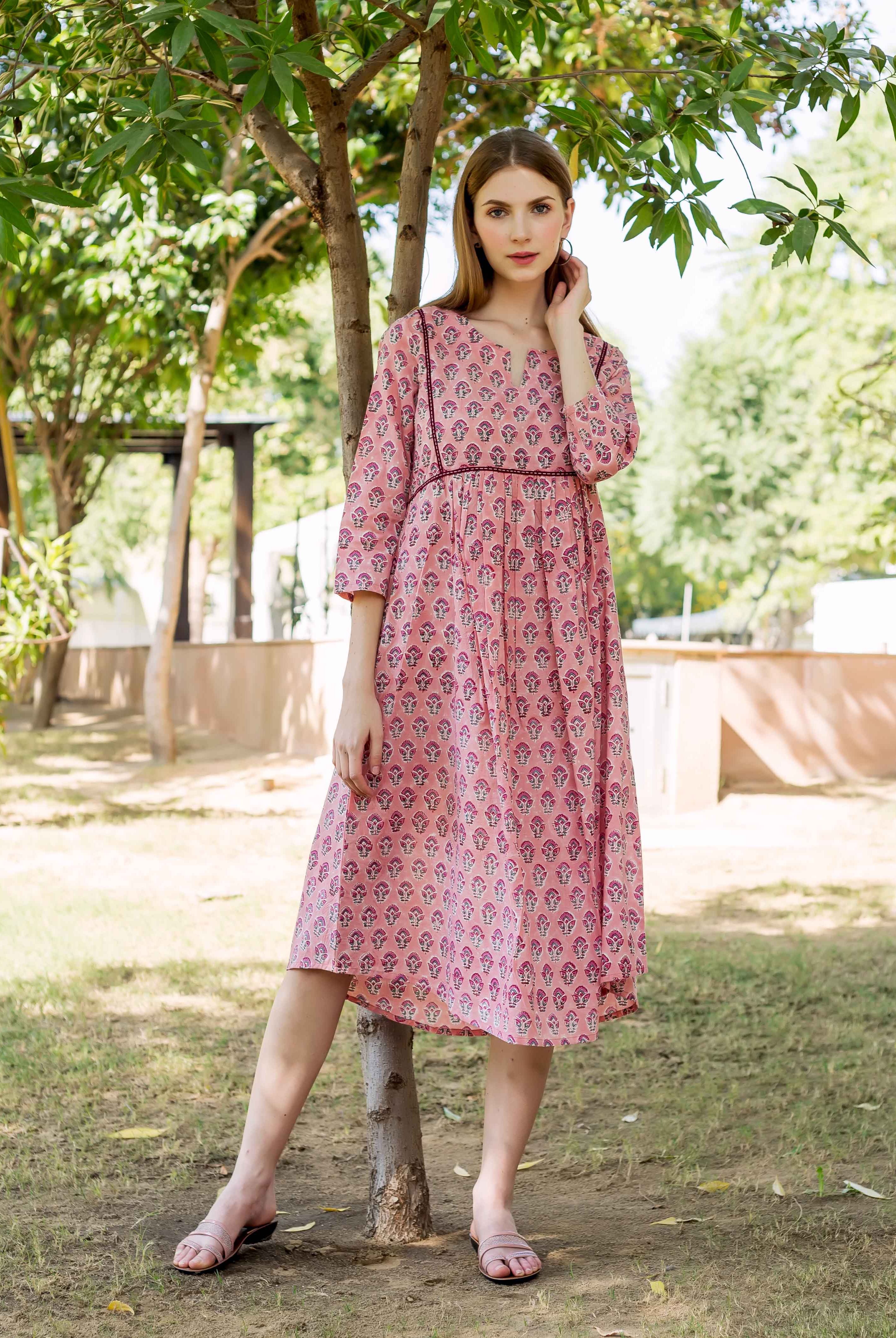 A model wearing a peach hand-block-printed dress with a floral pattern.