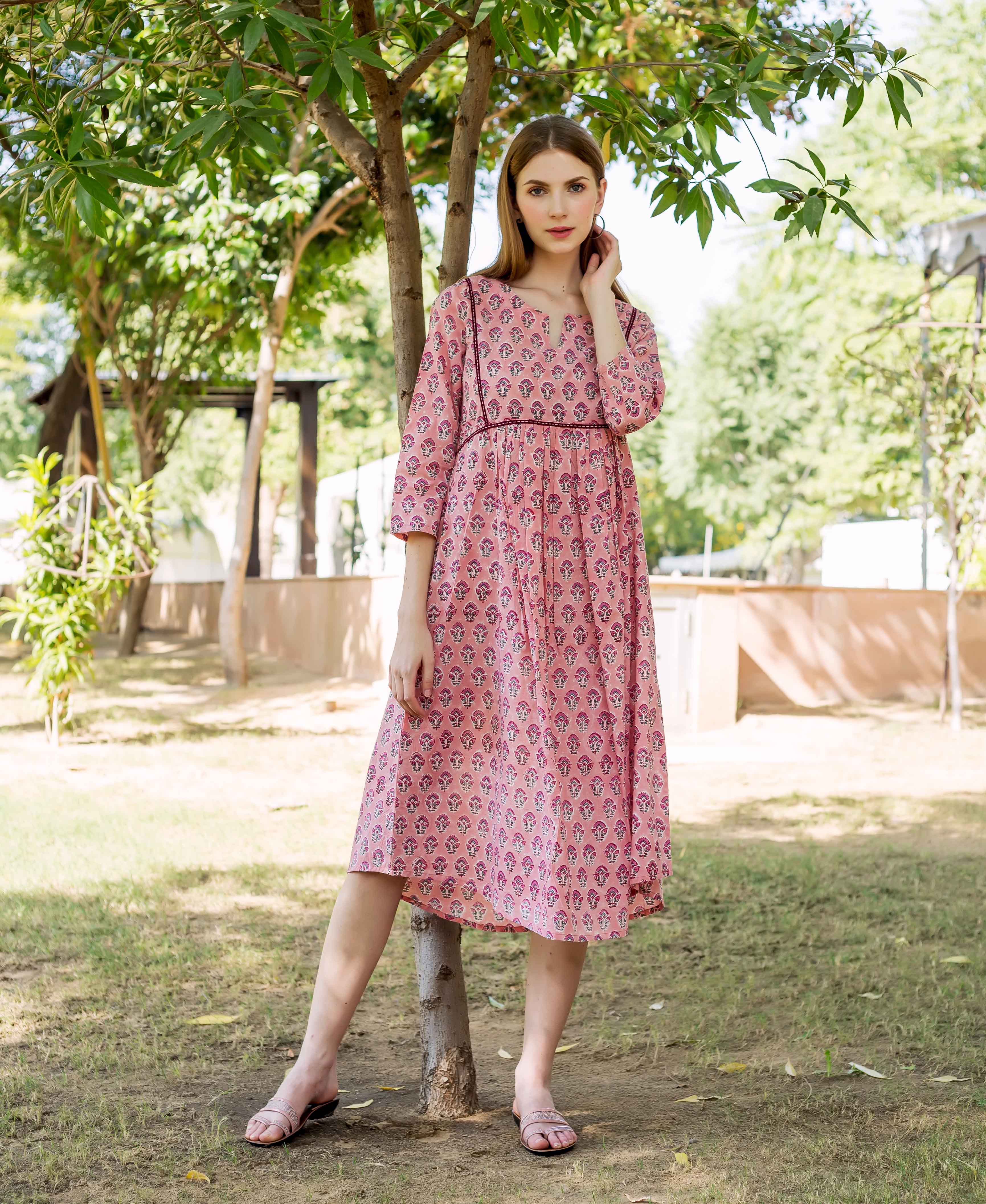 A model wearing a peach hand-block-printed dress with a floral pattern.