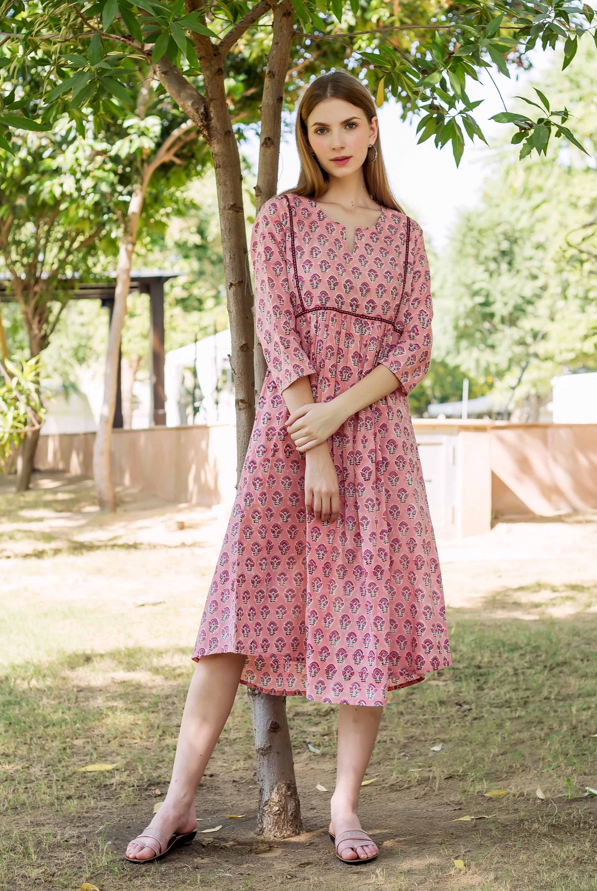 Peach hand-block-printed dress with pink, purple and white pattern, on a woman outdoors.
