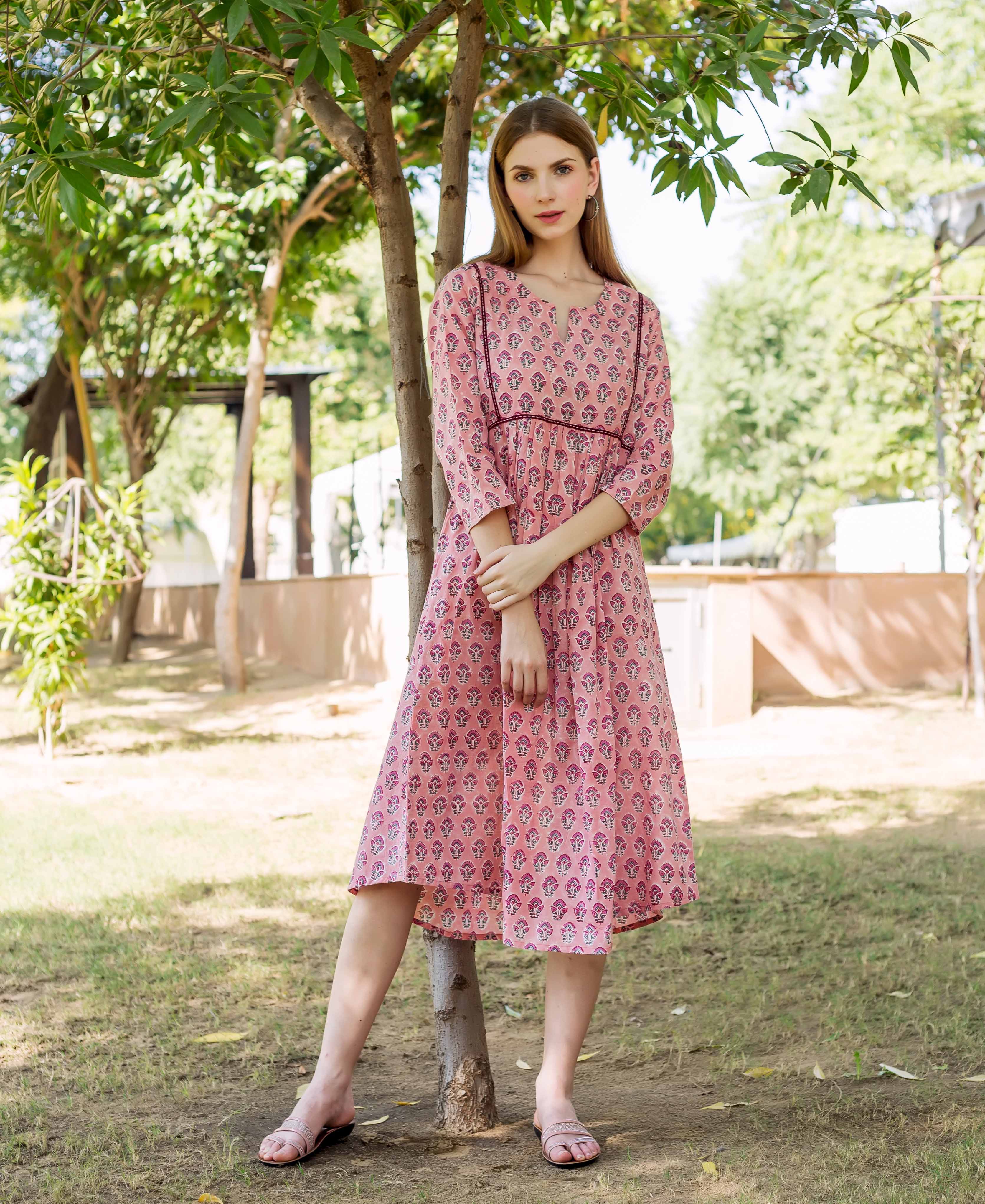 Peach hand-block-printed dress with pink, purple and white pattern, on a woman outdoors.