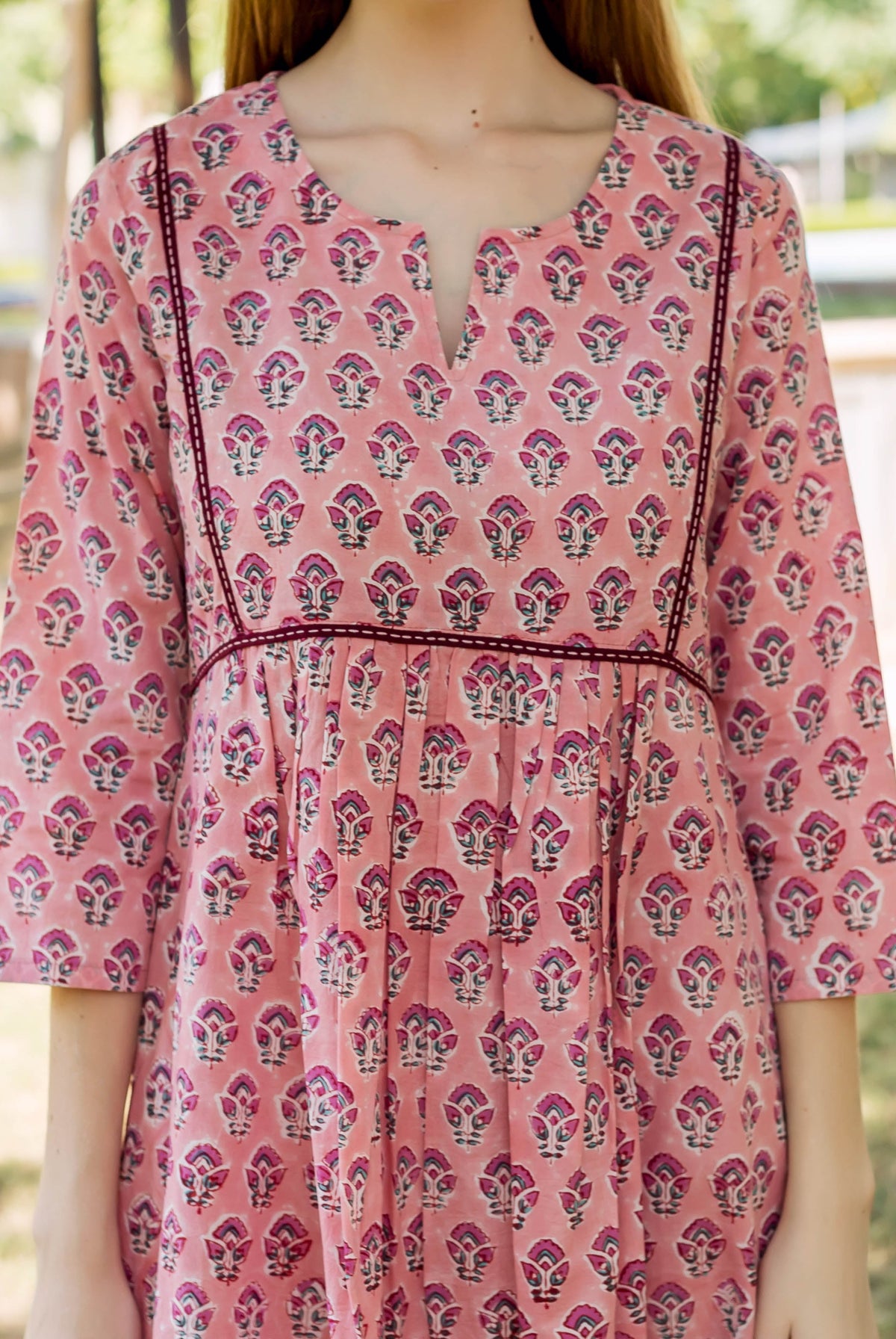 A model wearing a peach hand-block-printed dress with a floral pattern.