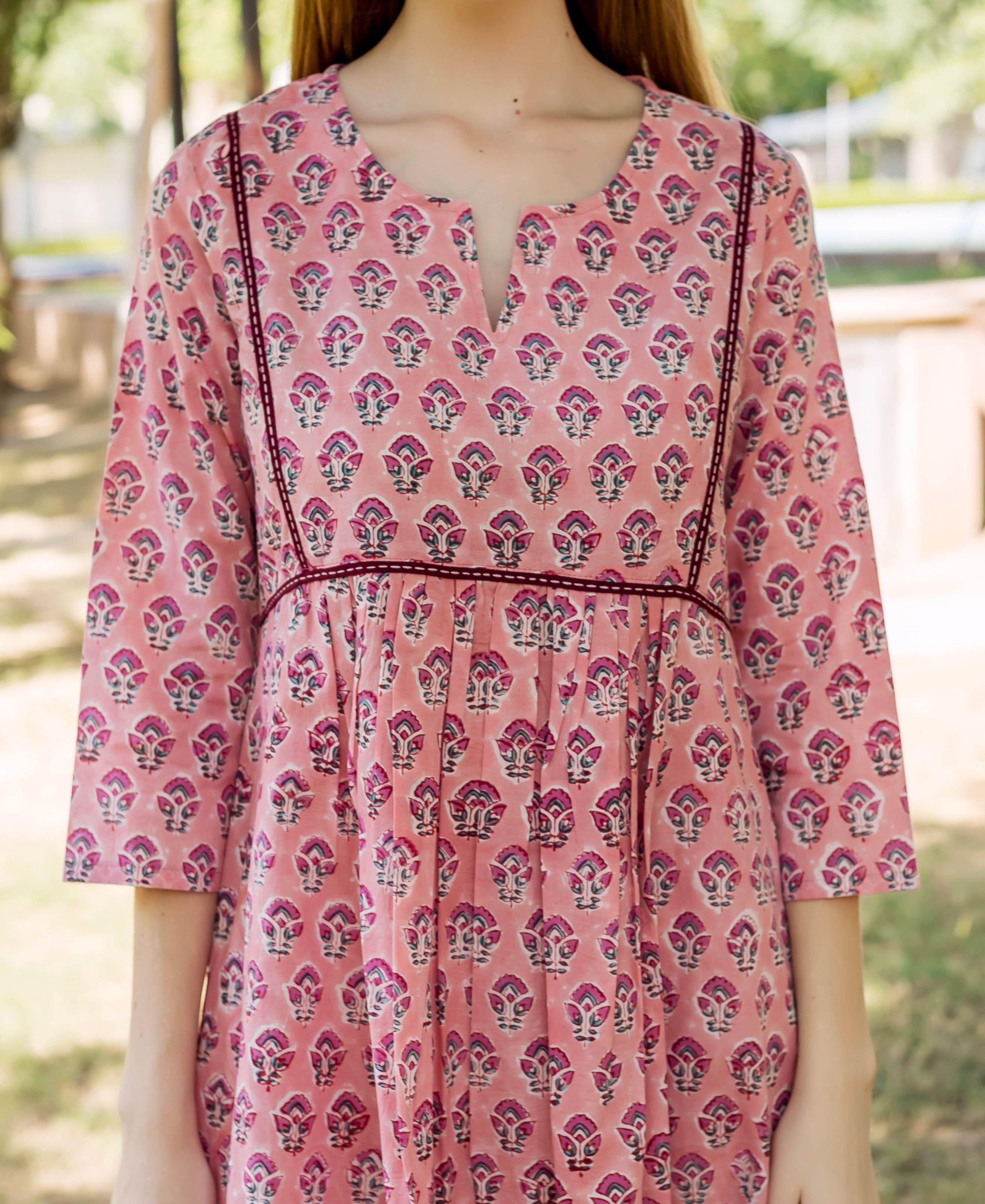 A model wearing a peach hand-block-printed dress with a floral pattern.