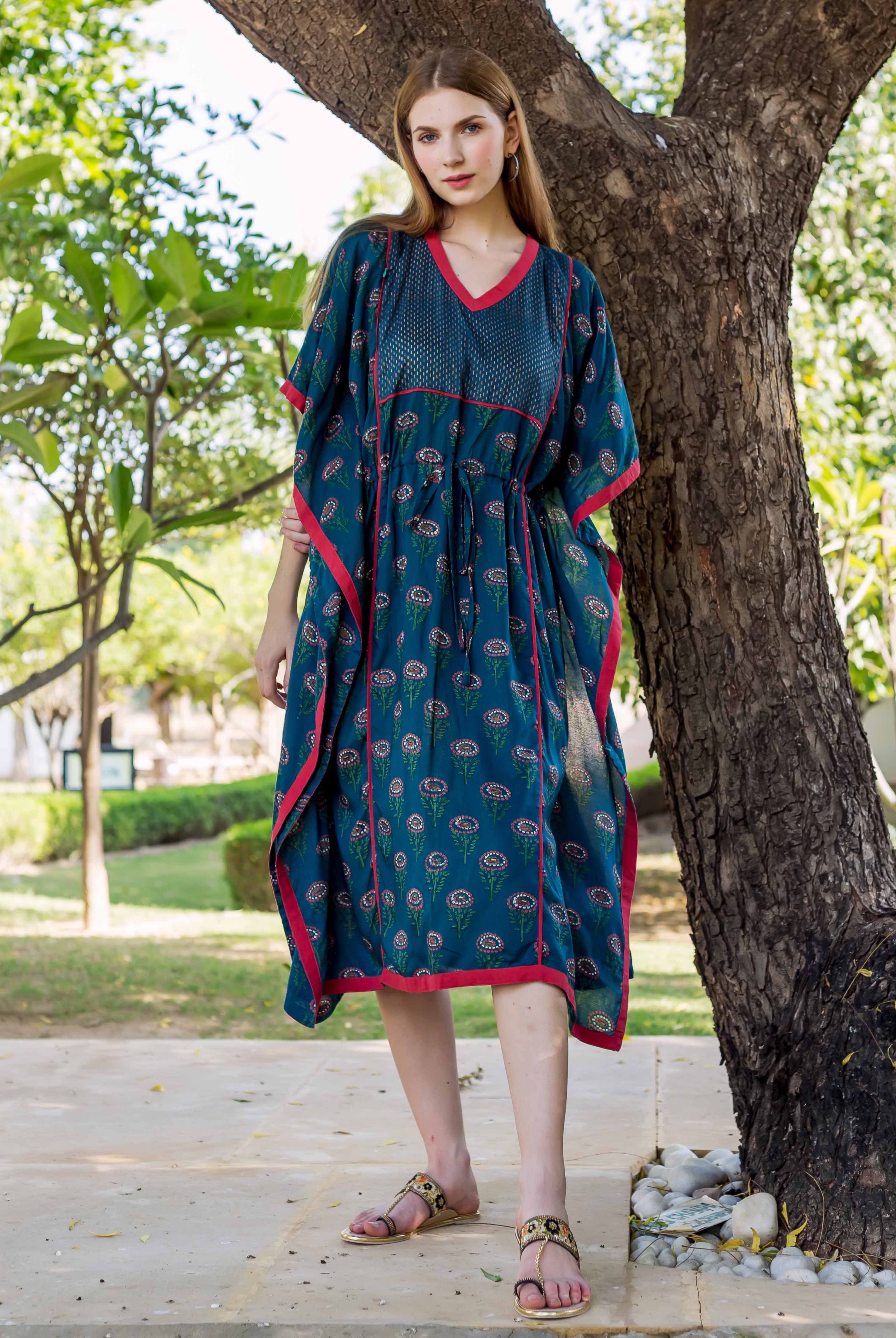 Peacock green kaftan with pink trim and floral print, on a model outdoors.
