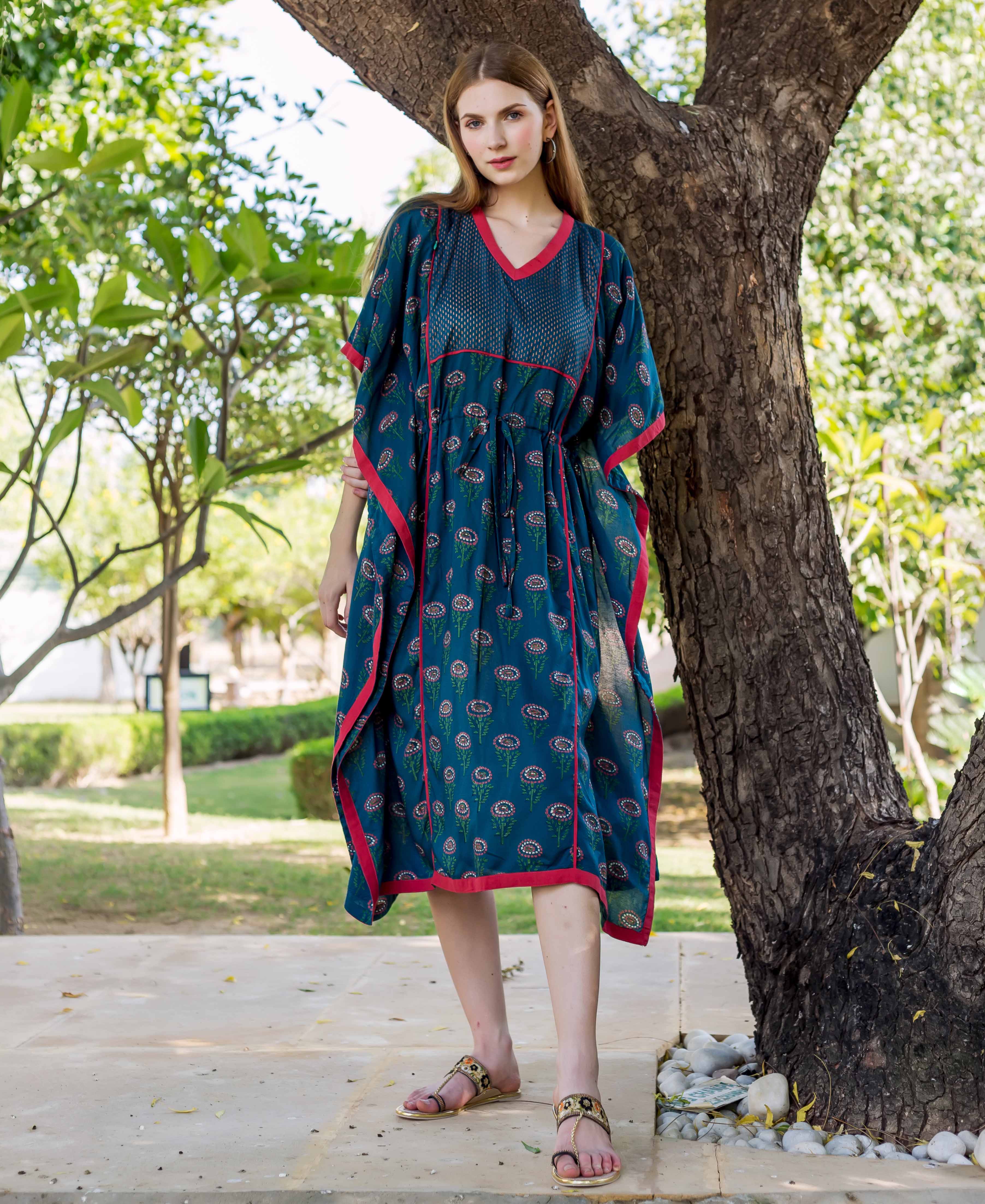 Peacock green kaftan with pink trim and floral print, on a model outdoors.