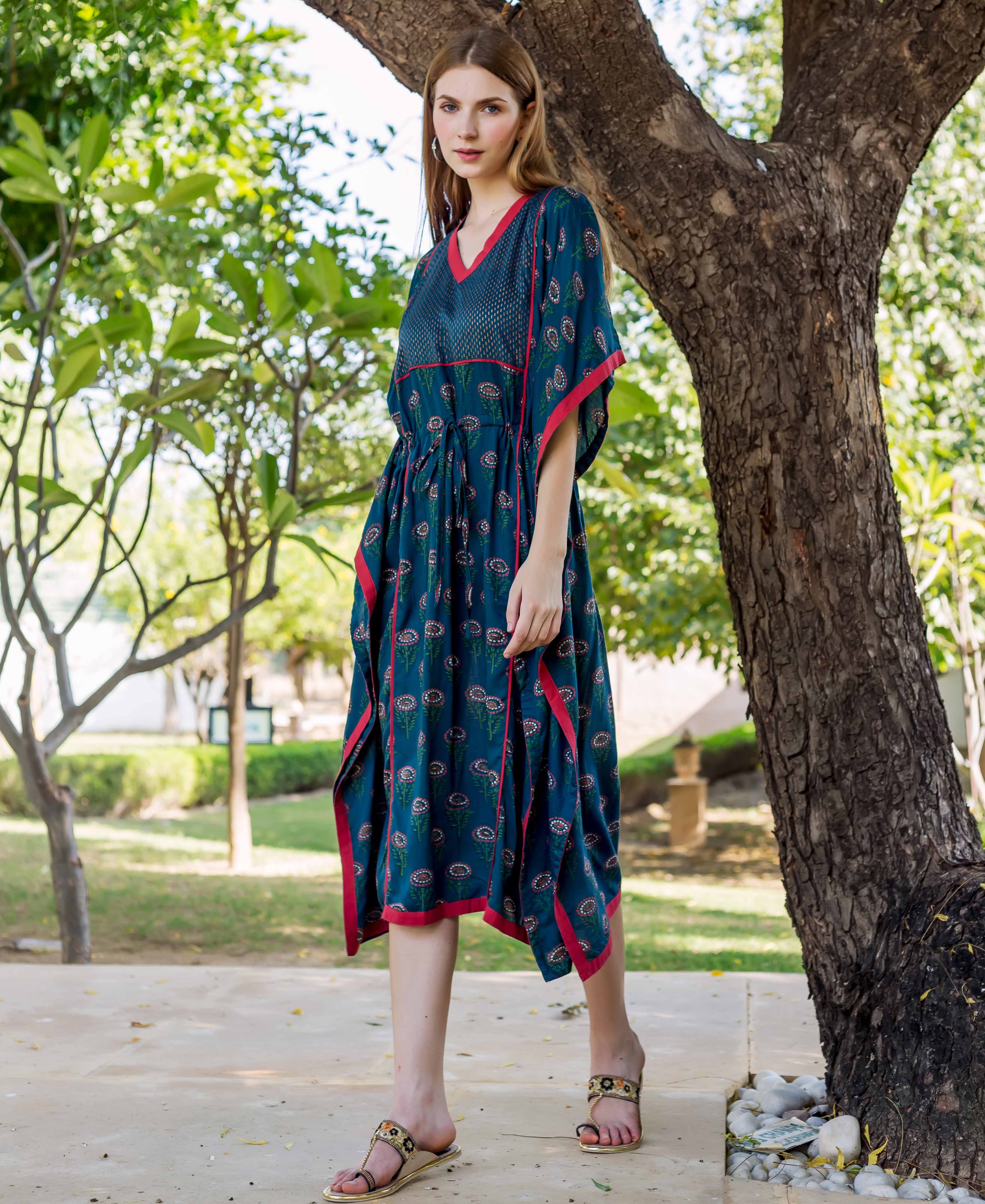 Standing model wearing a peacock green hand-block-printed kaftan with red trim and floral print.