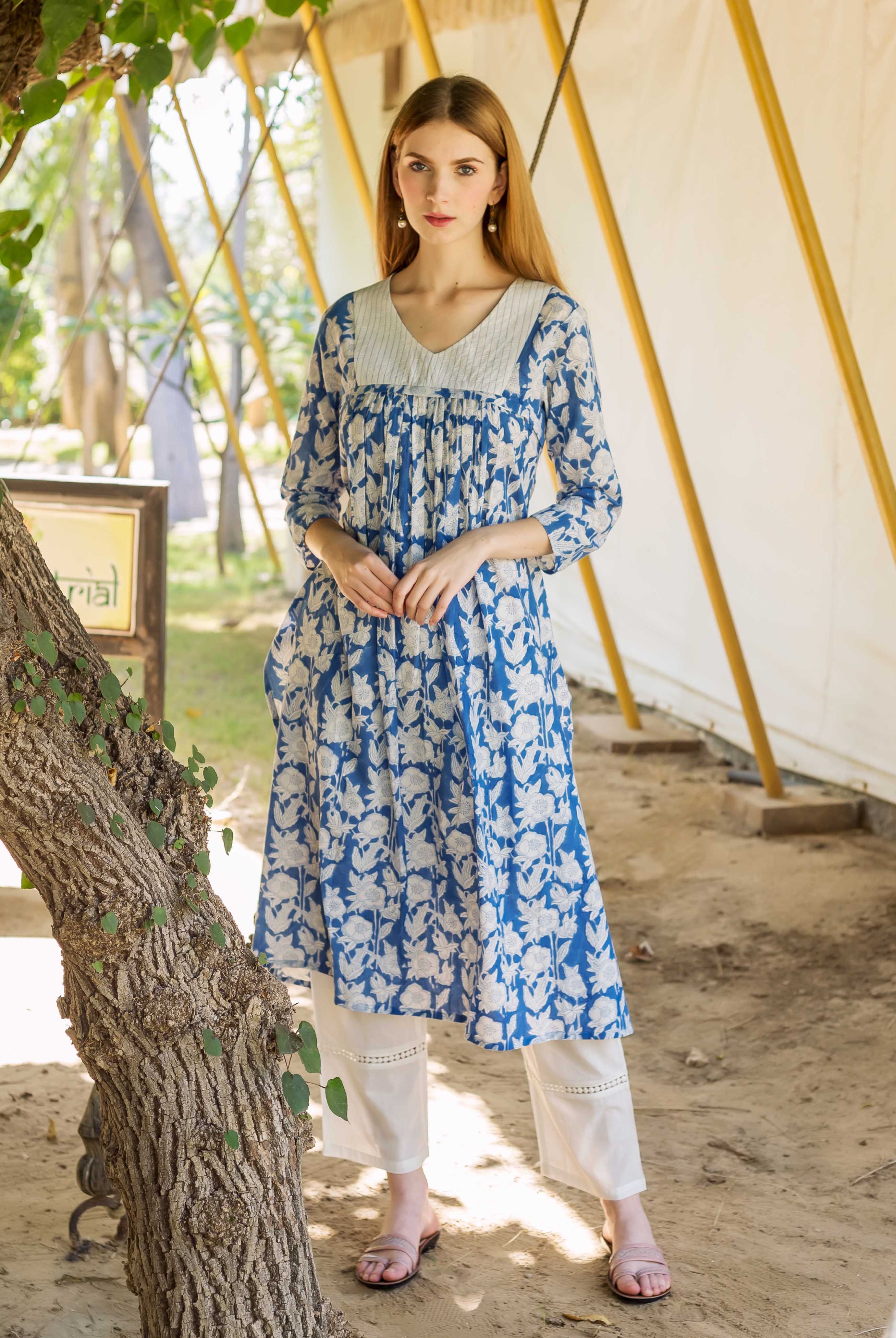 Full look of model in blue and white floral hand-block printed kurta with white pants.
