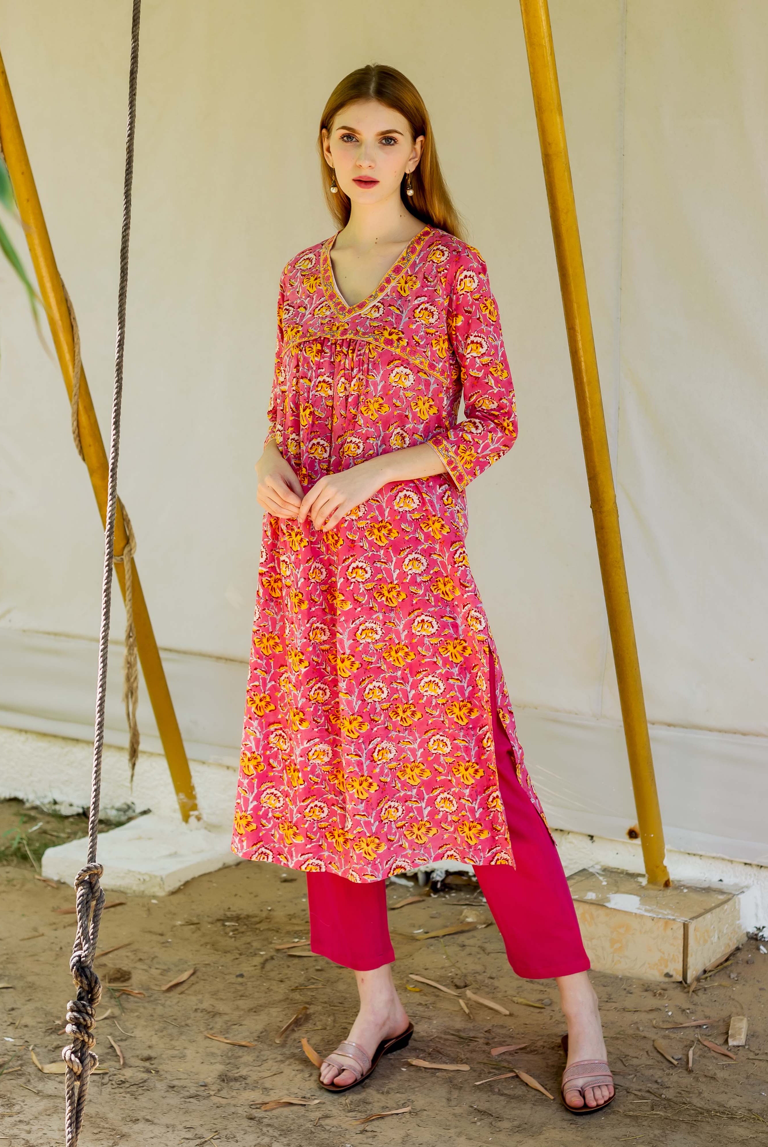 Woman wearing pink and yellow floral hand block printed V-neck maternity and nursing kurta.