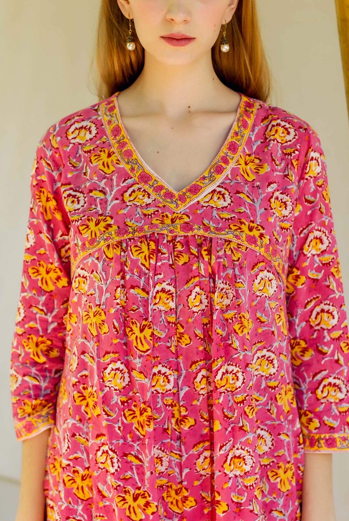 Close-up of a model wearing a pink hand-block printed floral kurta with V-neck.
