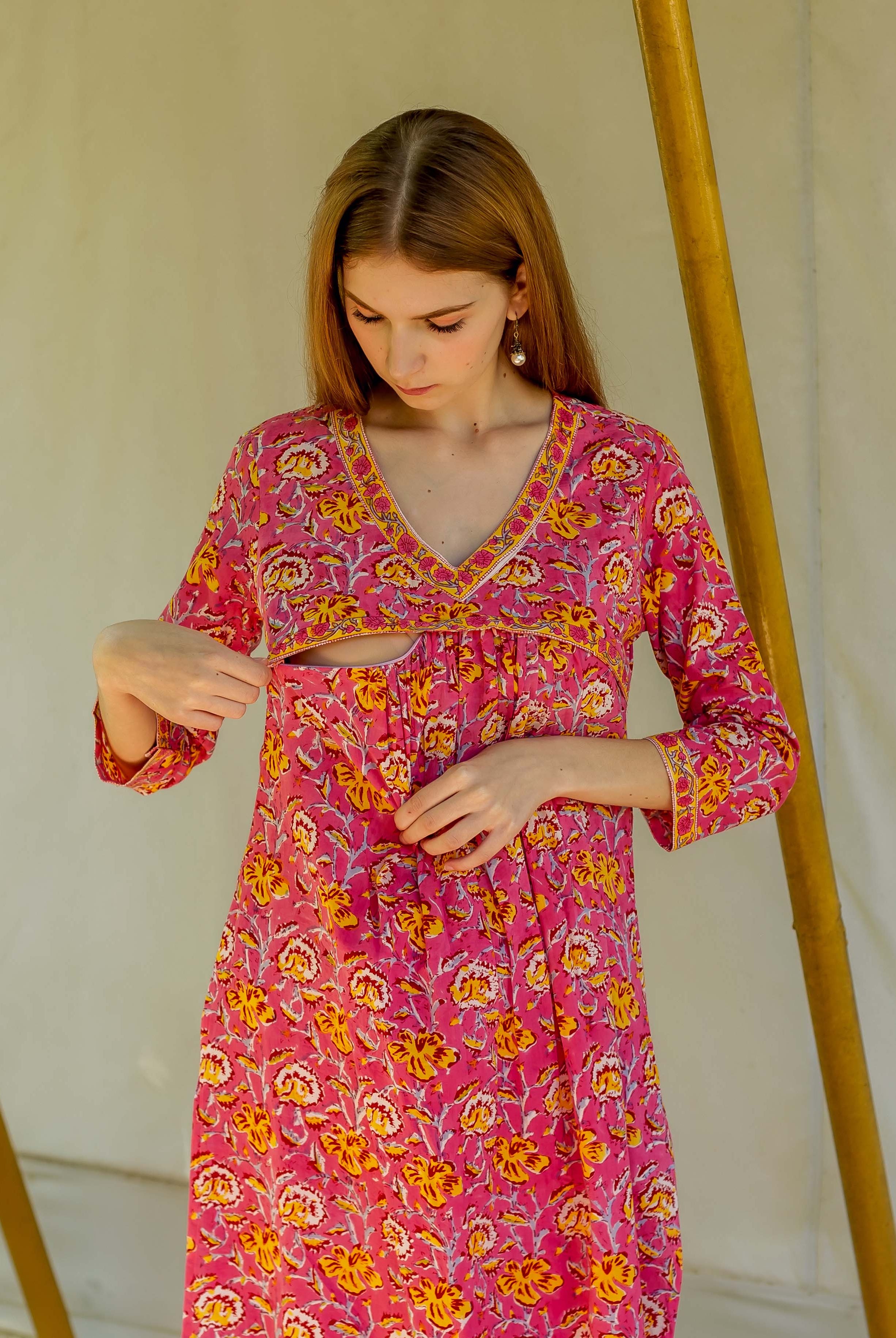 Woman in pink floral hand block printed kurta with yellow and orange flowers, exposed midriff.