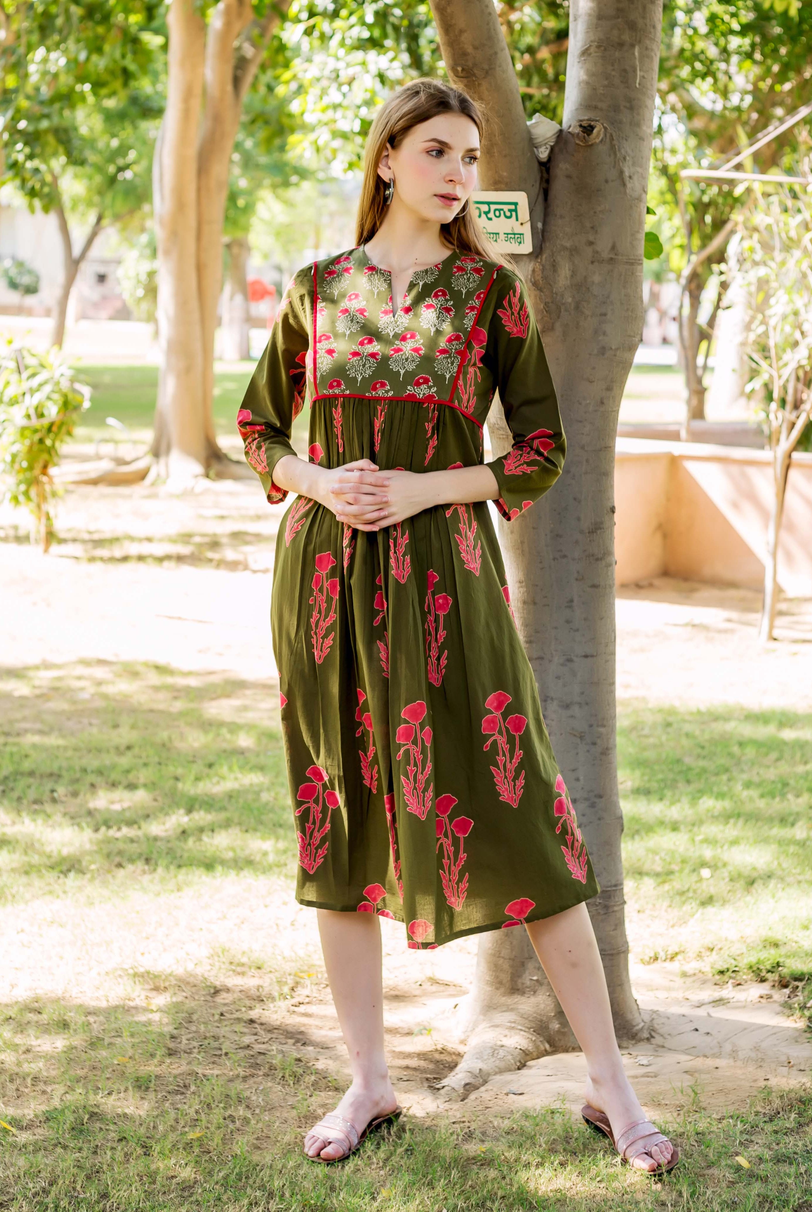 Olive green dress with red floral hand block print and pink sandals on a woman outdoors.