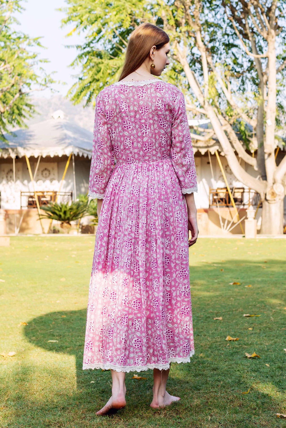 Full back view of woman in pink hand-block-printed dress with white floral motifs and lace.