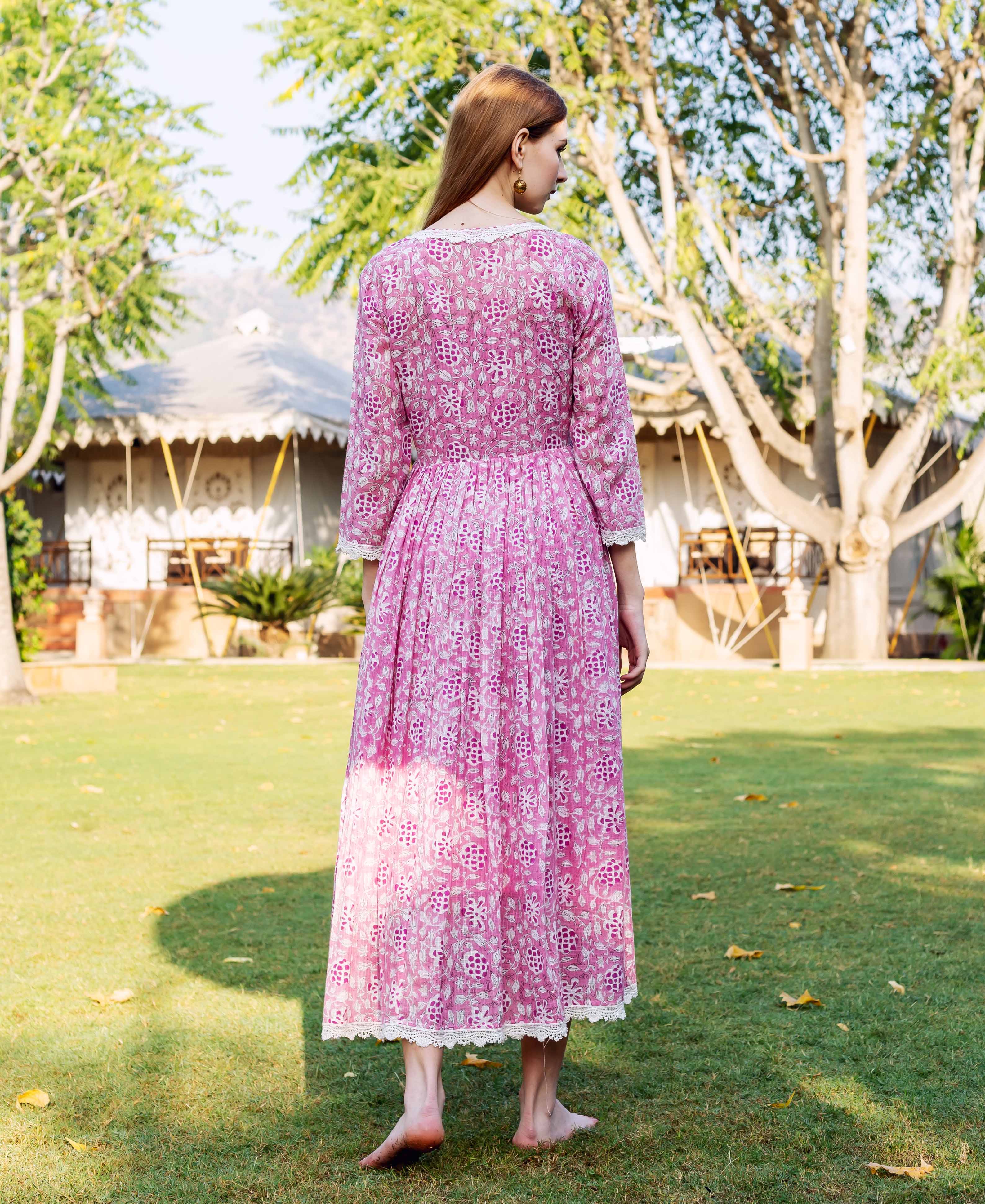 Full back view of woman in pink hand-block-printed dress with white floral motifs and lace.